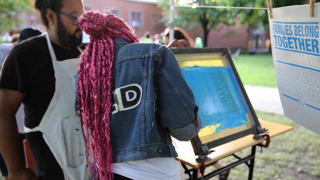 Multidisciplinary artist William Estrada teaches an event attendee how to screen print at his Mobile Street Art Cart project. The cart brings free, culturally relevant art workshops into Chicago neighborhoods.