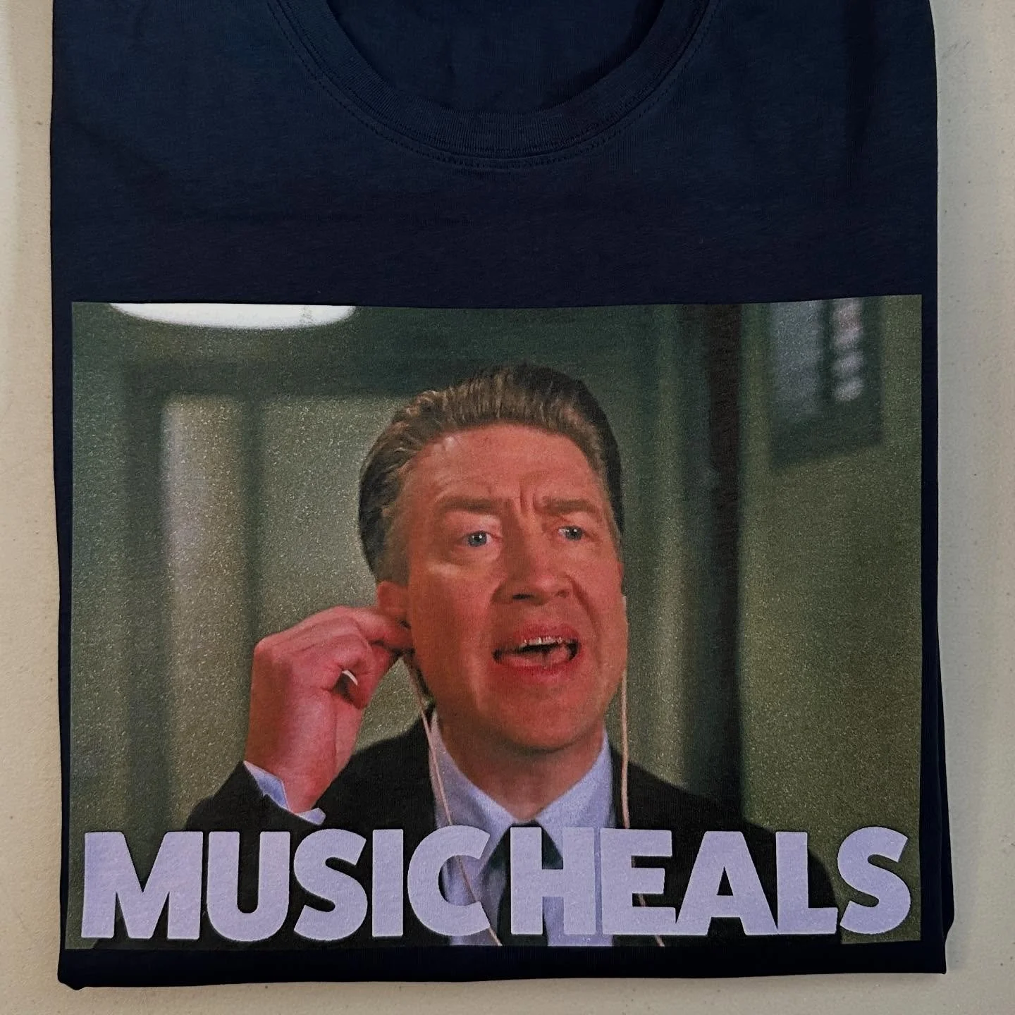 Music Heals 
David Lynch - Twin Peaks 
Navy Blue Tee 

https://goaheadmerch.com/recent-additions/david-lynch-music-heals-tshirt