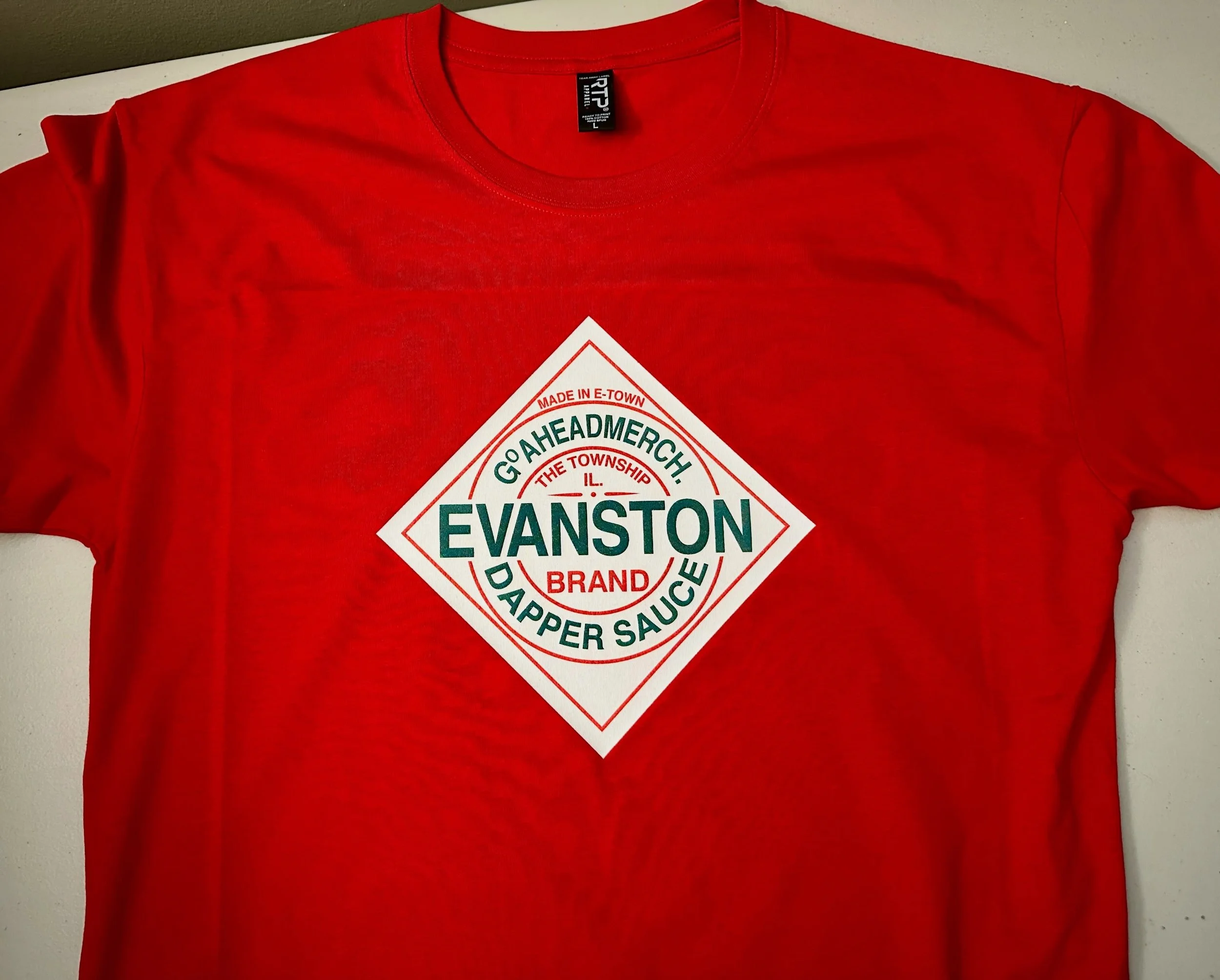 Dapper Sauce 
Evanston Brand
Red Tee 
.
https://goaheadmerch.com/evanston/evanston-dapper-sauce