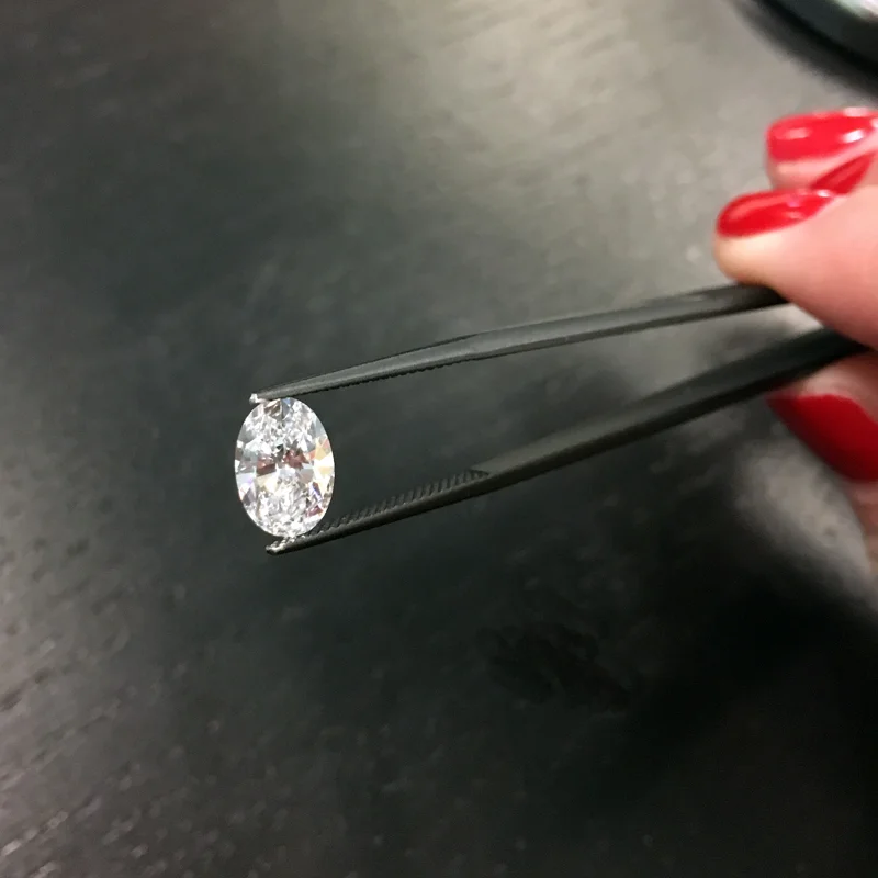 loose lab grown oval diamond in tweezers