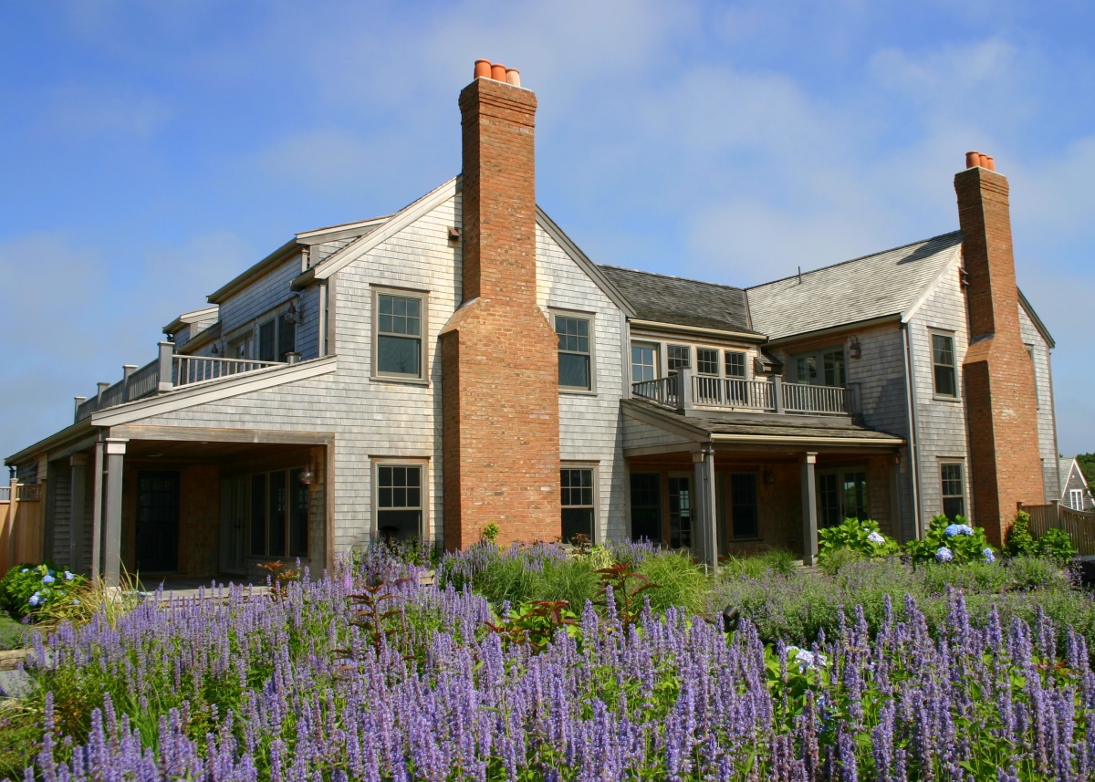 Custom grey shingle home on Nantucket with hydrangea and stone walls.