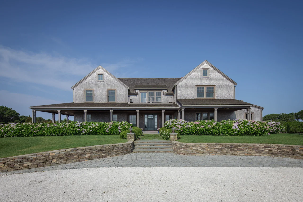 Custom grey shingle home on Nantucket with hydrangea and stone walls.