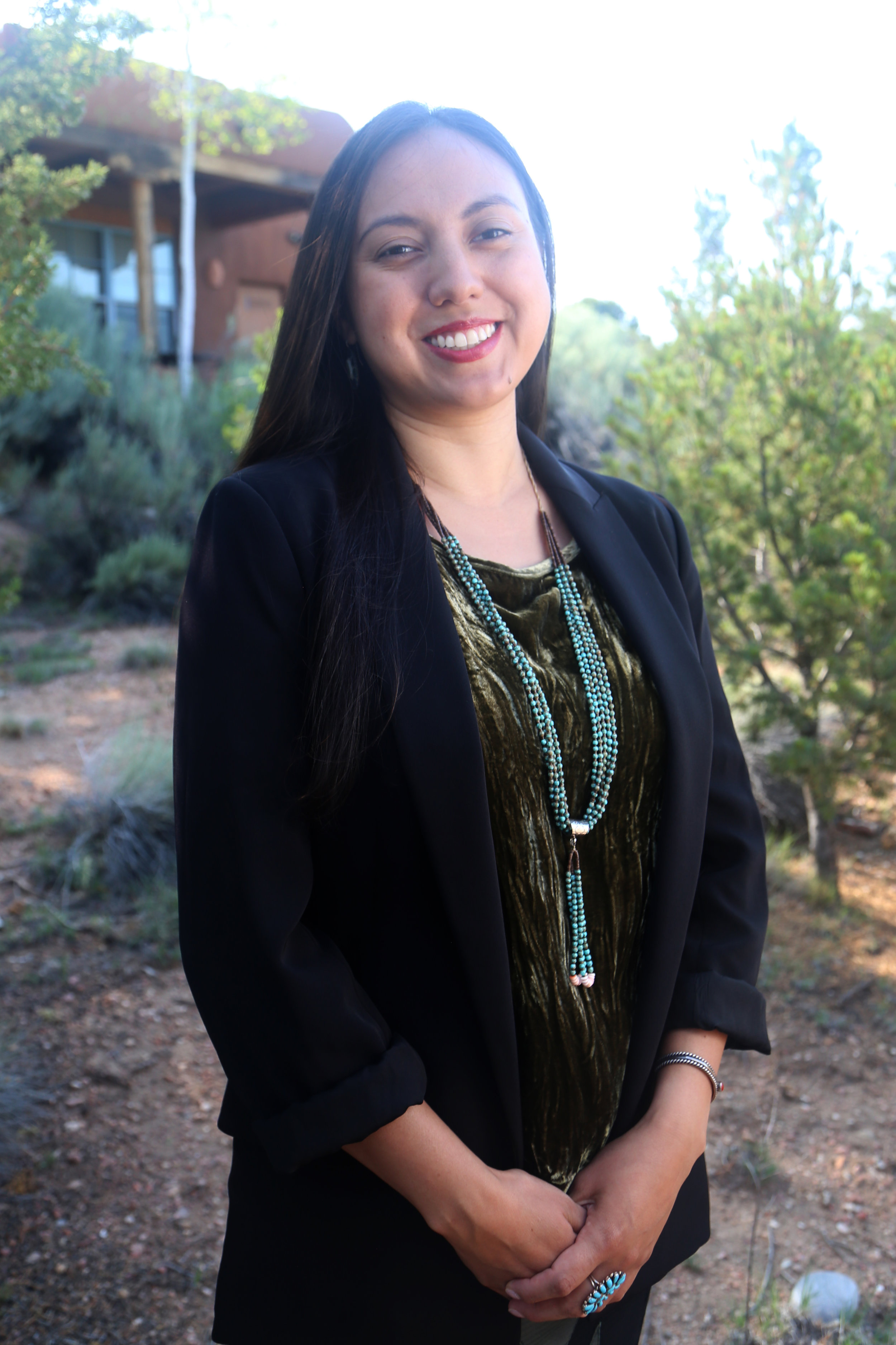 photo of Diné woman with light skin tone and long hair, smiling while standing outside