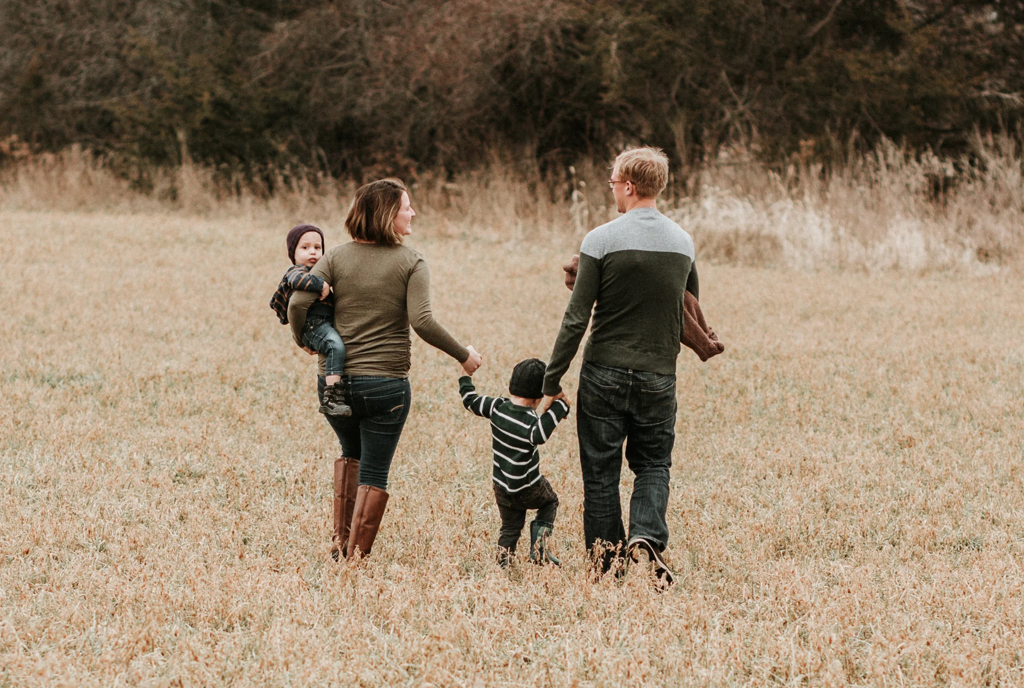 family walking through field holding hands