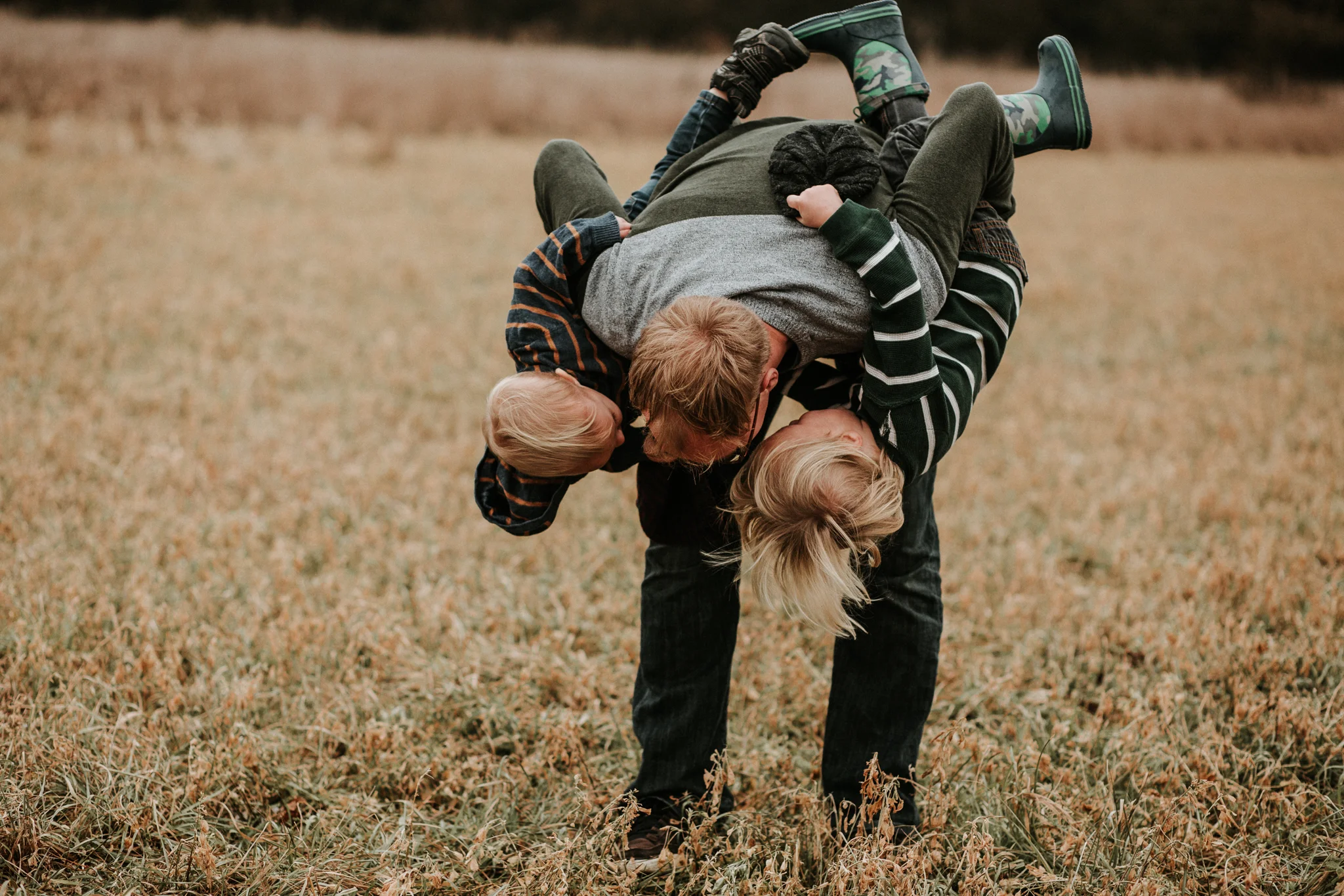 dad playing with sons in field