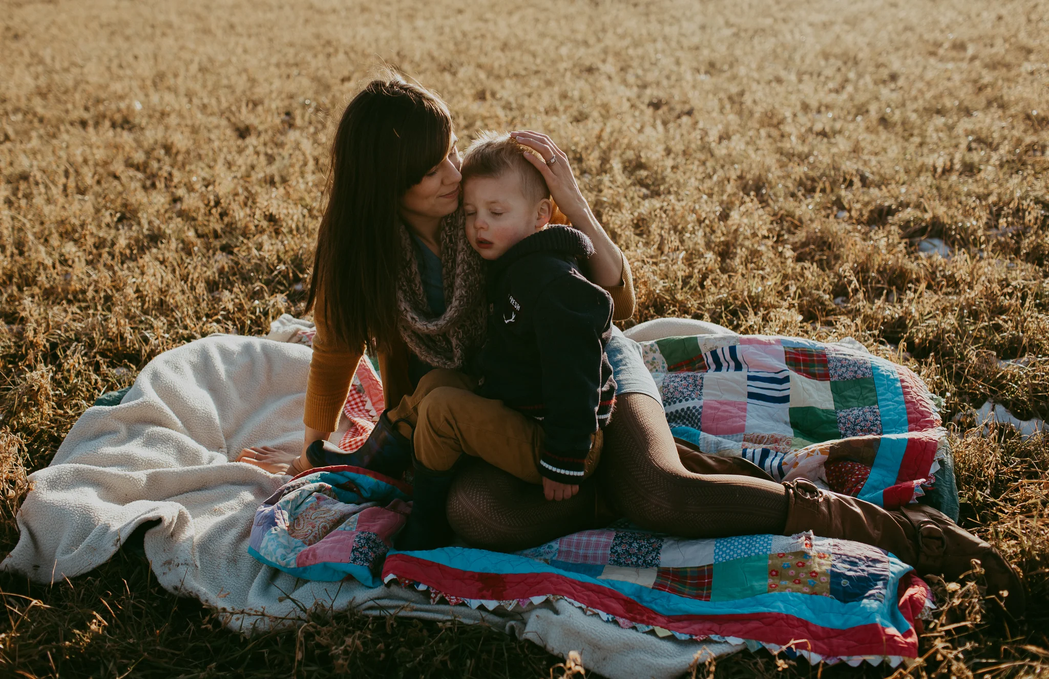 mom holding son on blanket