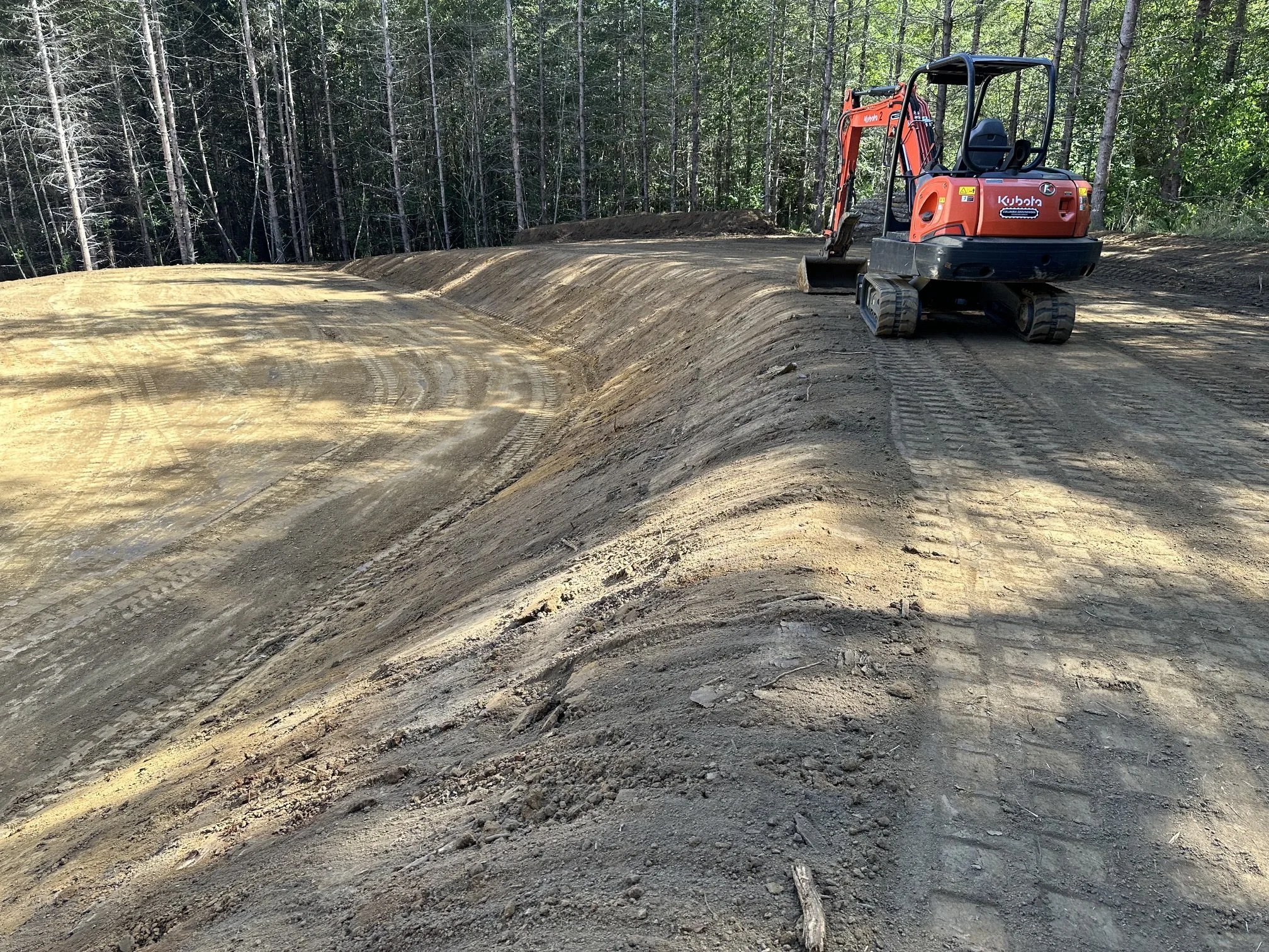 Mini excavator grading a road cut