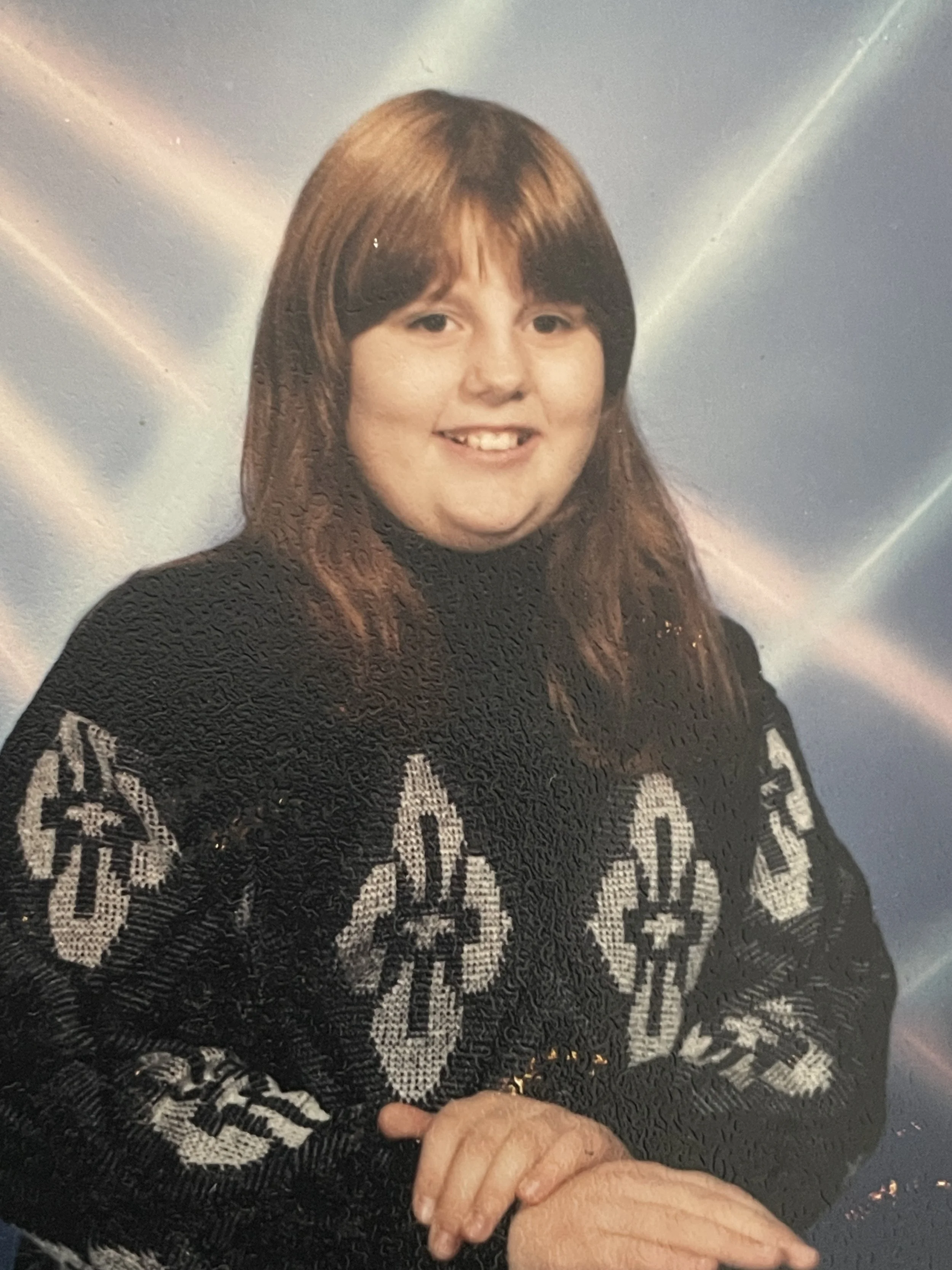 9 year old Meag wearing a cozy black sweater for picture day, her hair is down and she has bangs.