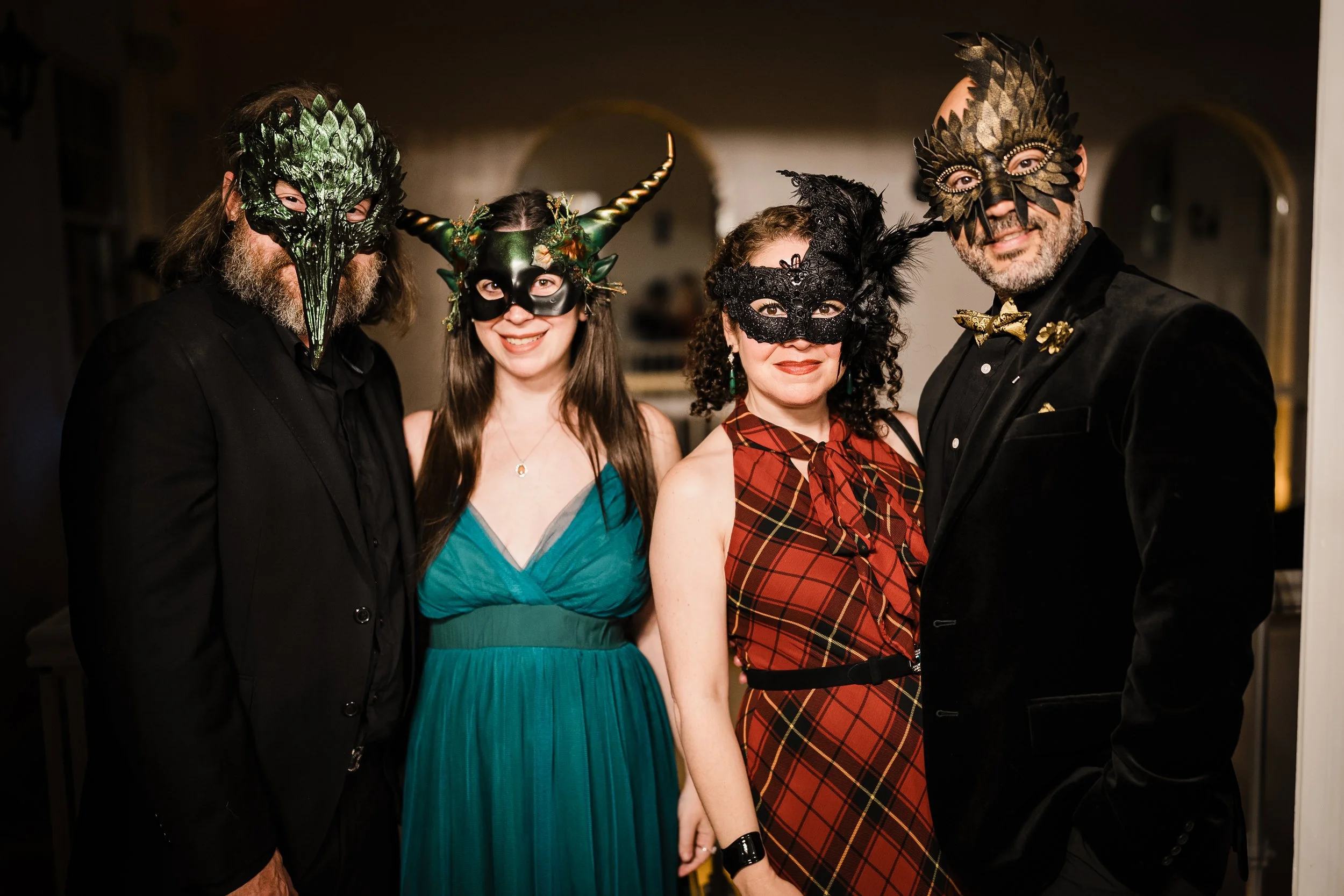 A group of four adults wearing elaborate masks at a costume event.