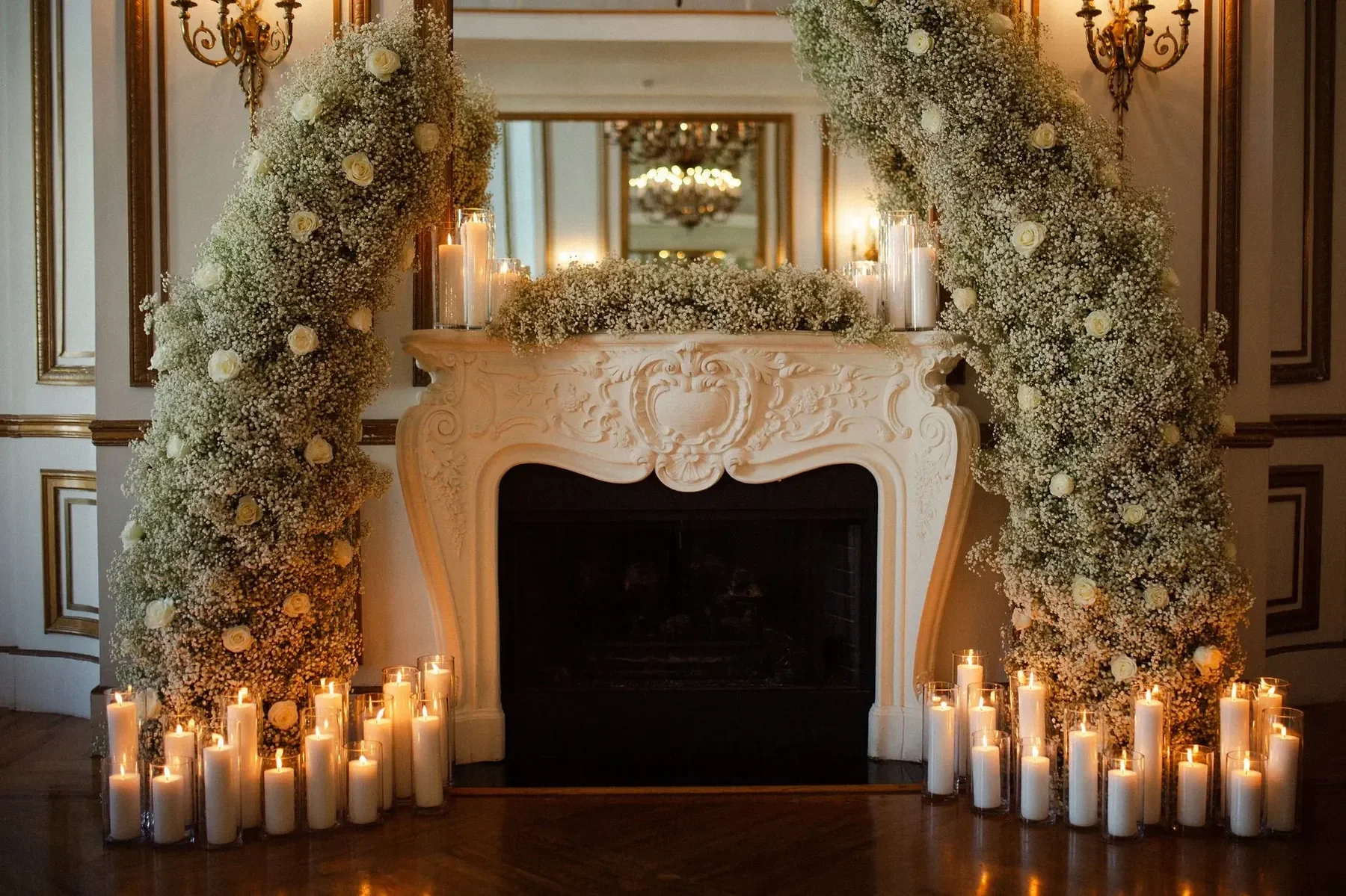 A decorated fireplace mantel with white flowers and candles for a wedding or event.