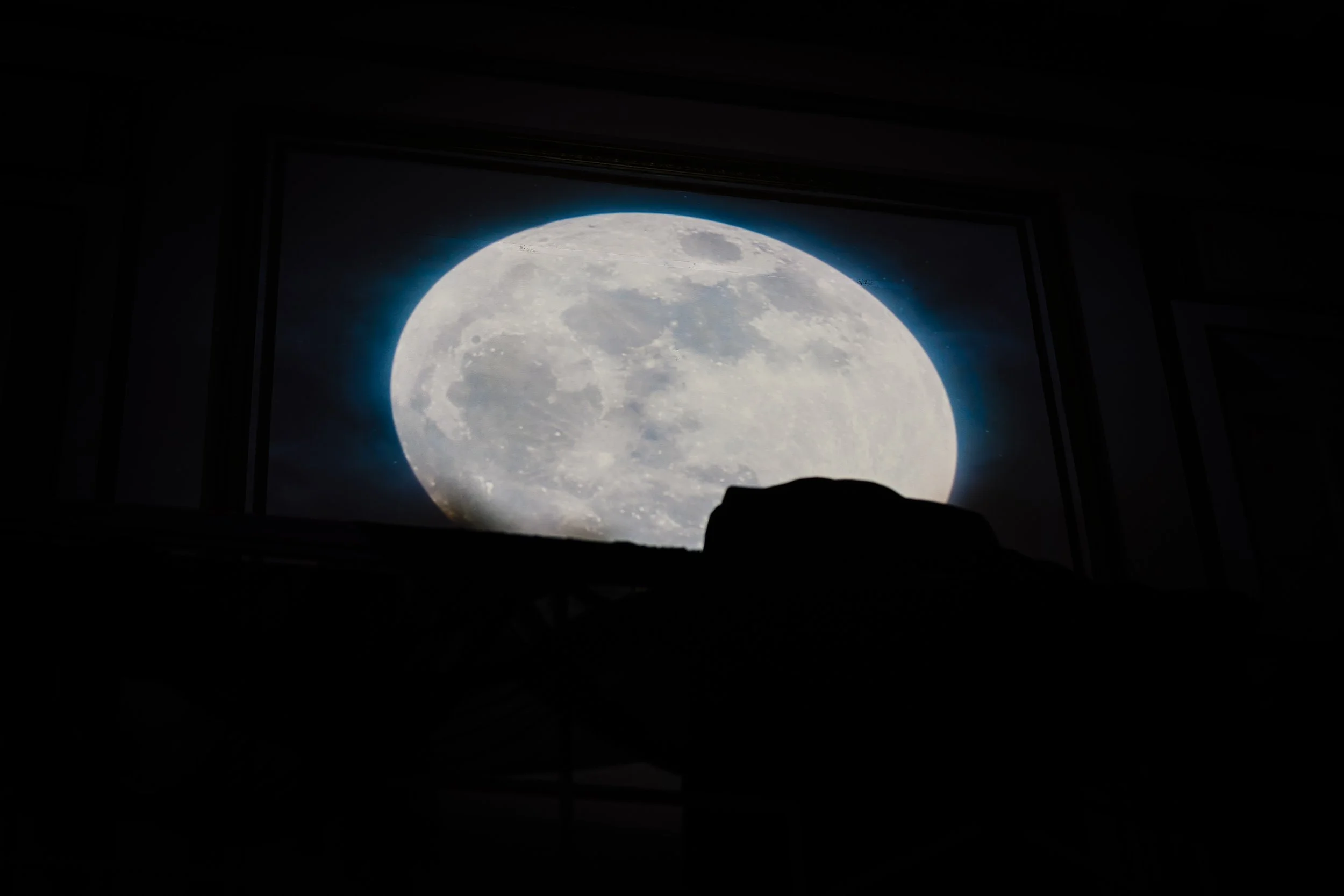 View of the full moon through a window with dark edges.