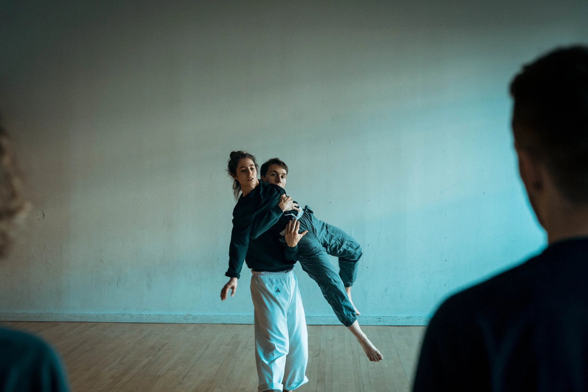 Two dancers rehearsing, with two spectators watching in the foreground.