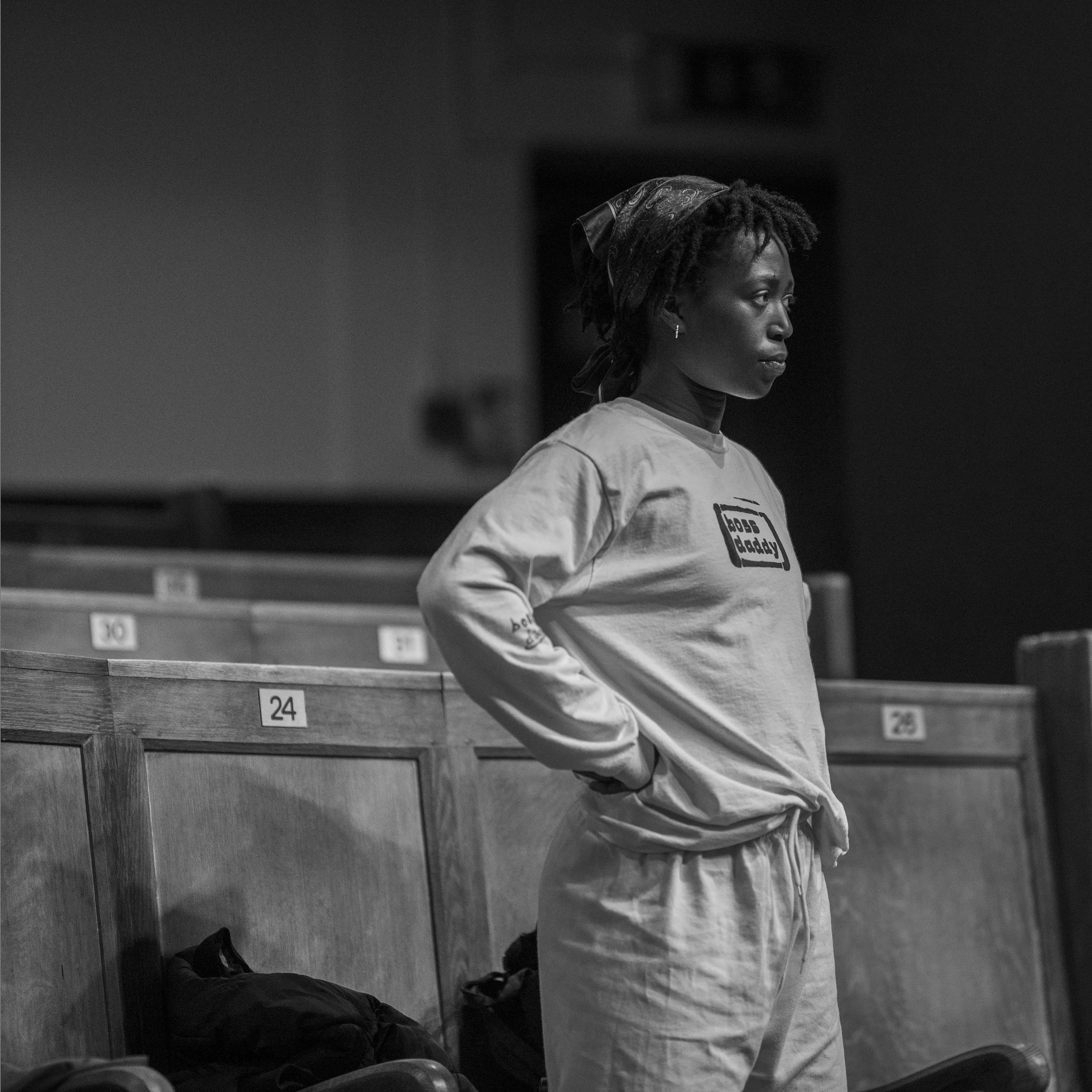 A female dance students watching people work on stage during a workshop.