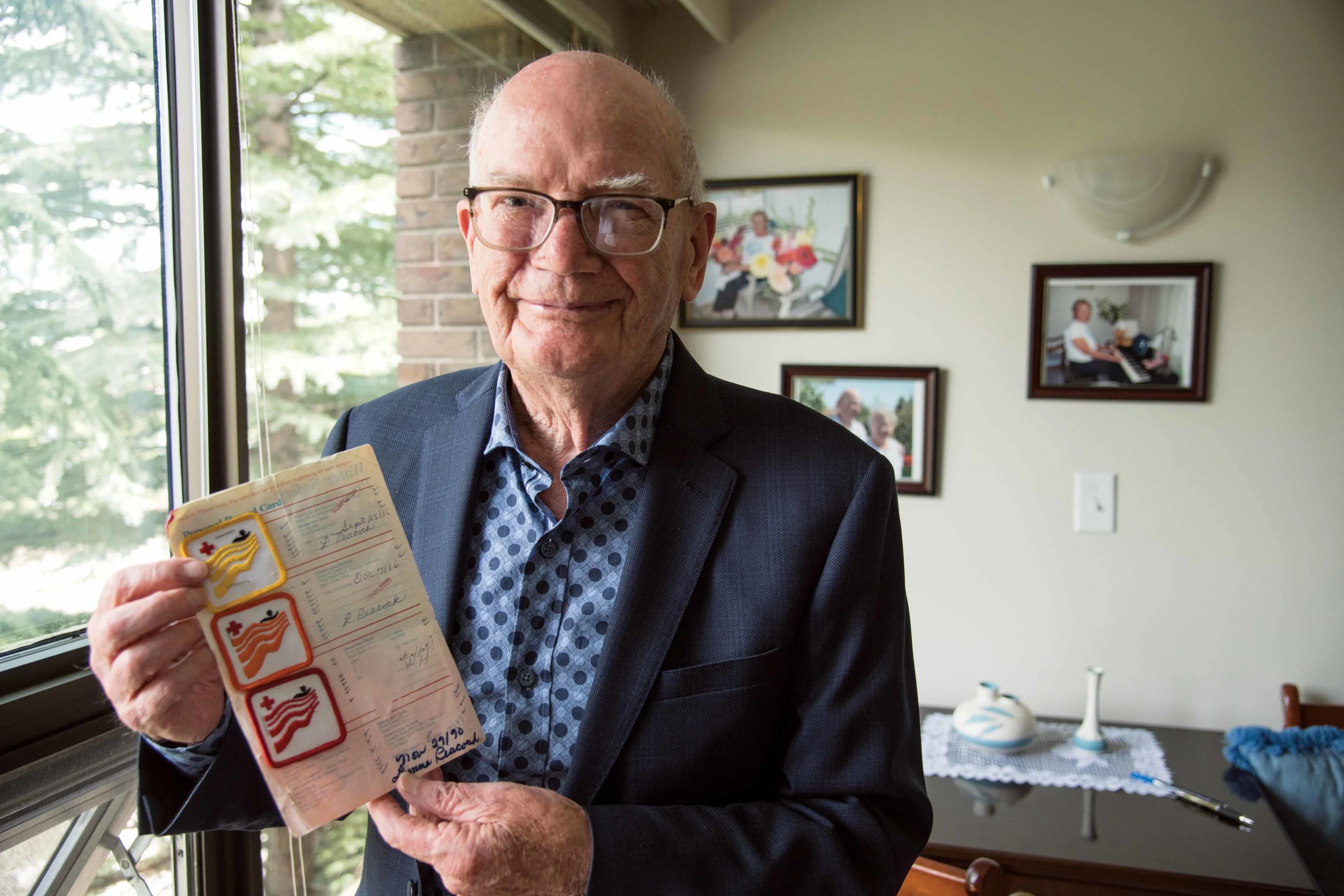Ron Freckleton holds his wife, Joan’s, swimming badges that she received when she learned to swim as an adult. Ron and Joan enjoyed regular aquacize classes together even as her dementia progressed, a routine he follows to this day. Photo by Jared Sych.