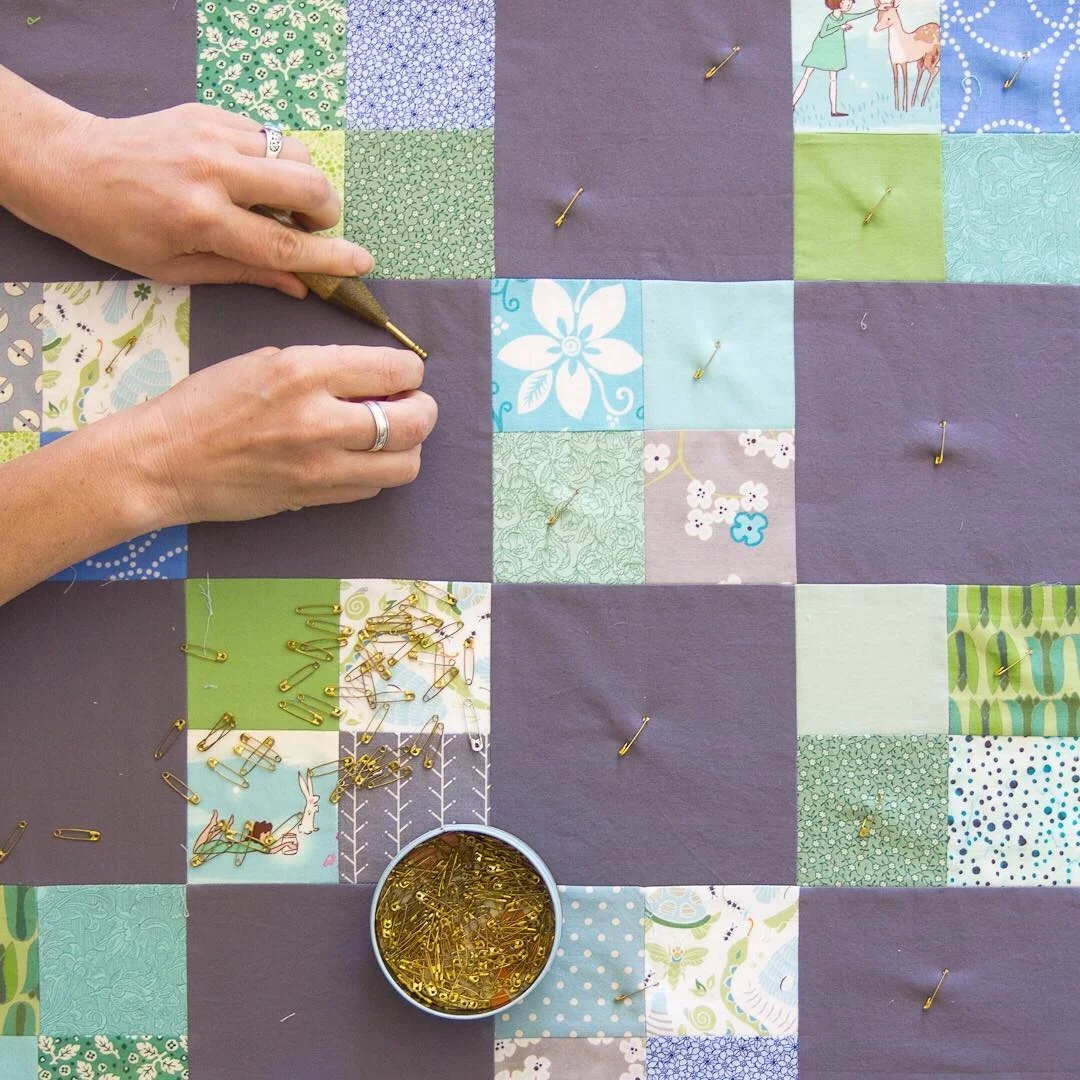 Angela from Hello, Quilting pinning a woodland-themed baby quilt.