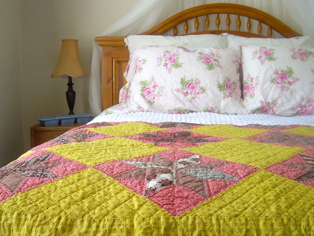 Antique Chrome Yellow and Double Pink Quilt on Wooden Bed via www.helloquilting.com