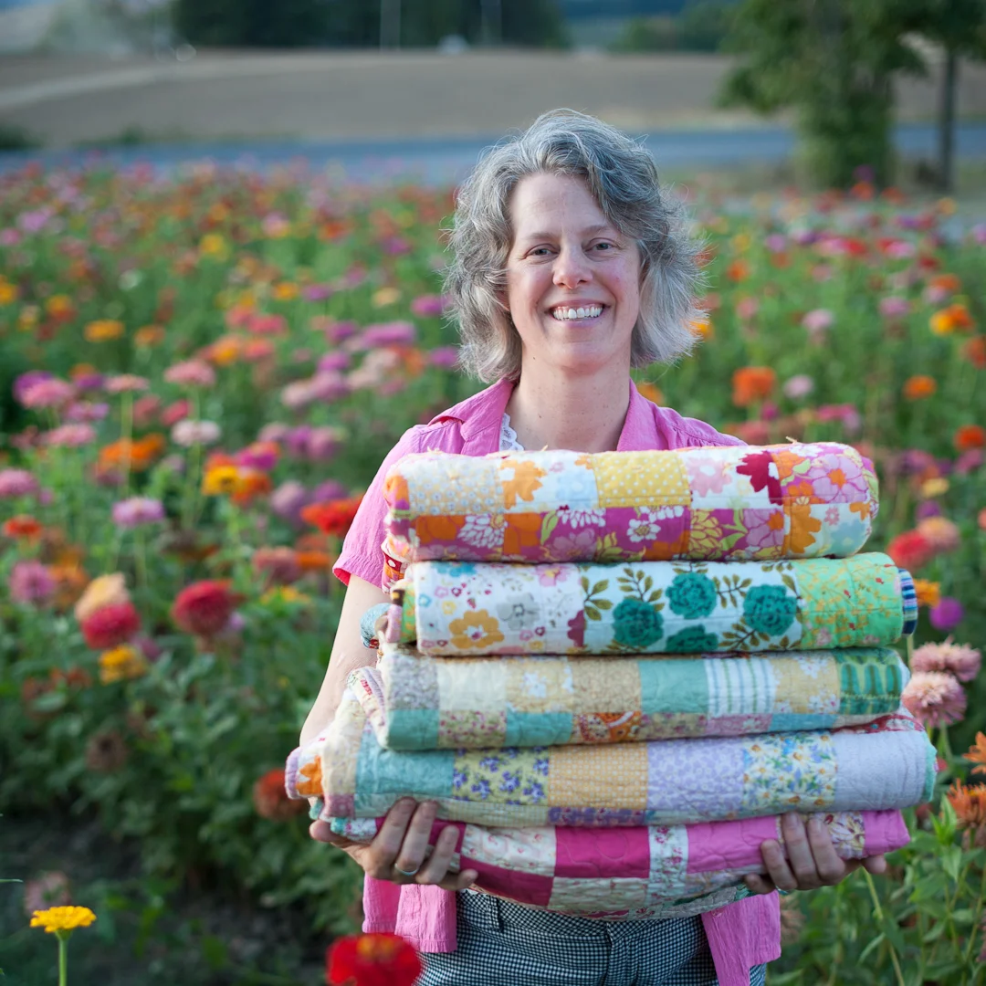 Angela May Waller holding her quilts via www.angelamaywaller.com