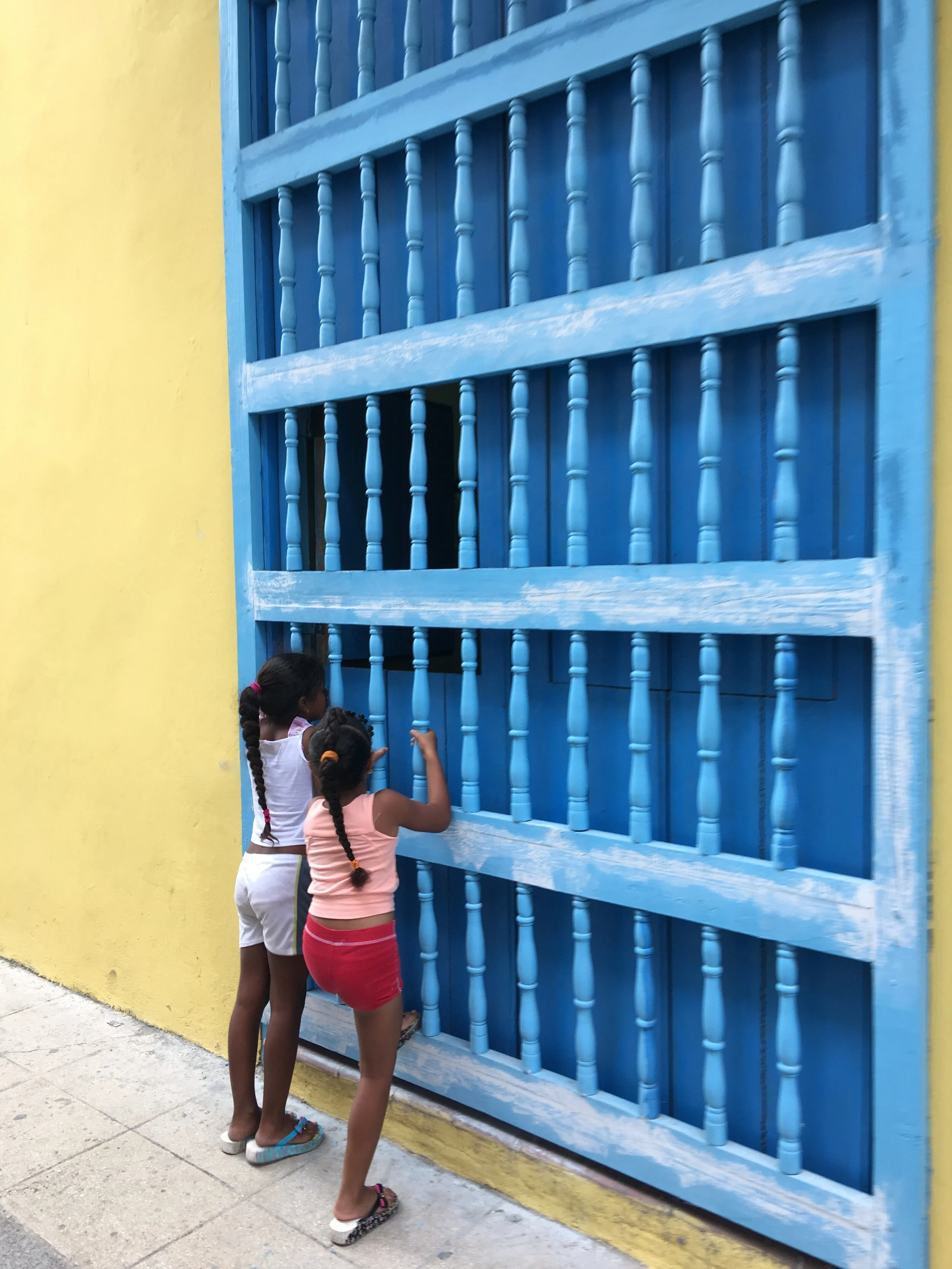 Two little girls watching men roll cigars