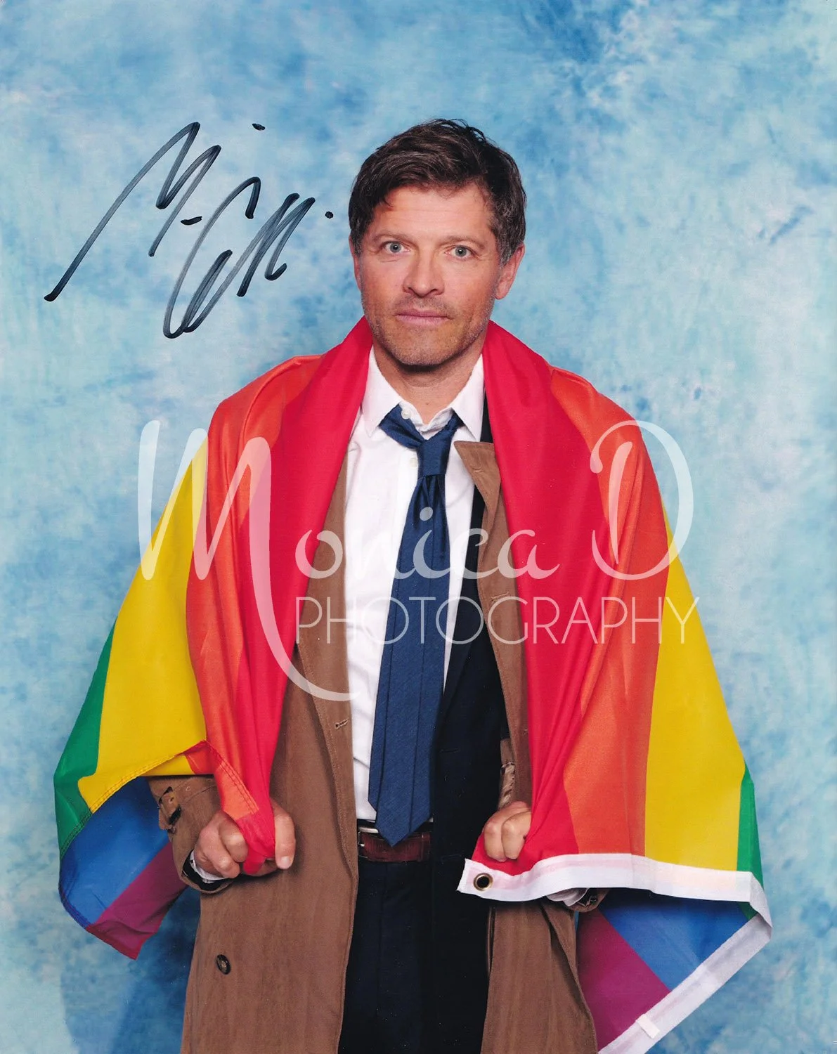 Misha Collins in costume as his Supernatural character, Castiel, draped and holding a Pride flag