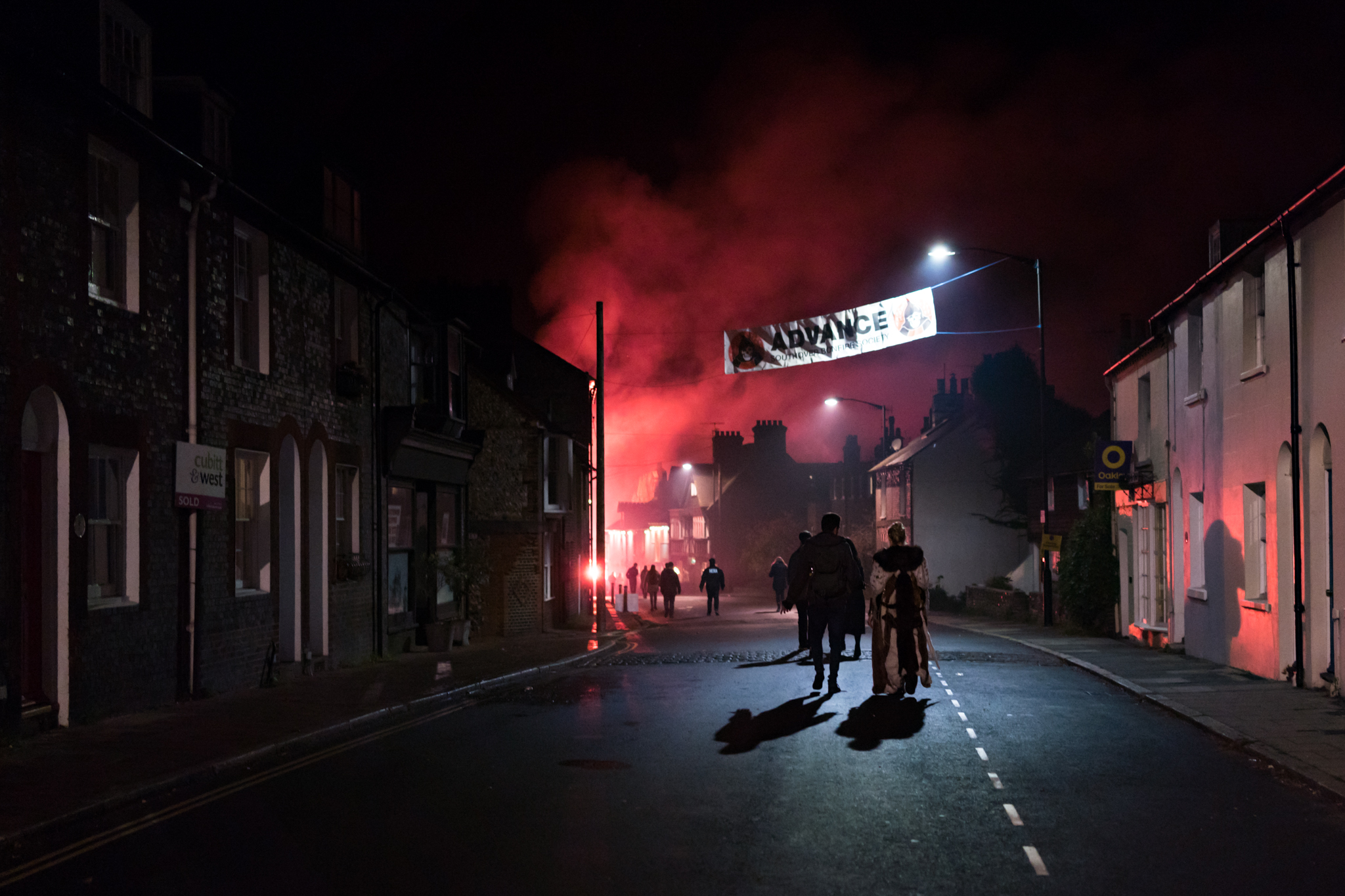 A couple walk home in the early hours of the morning as flares and firecrackers are still being lit