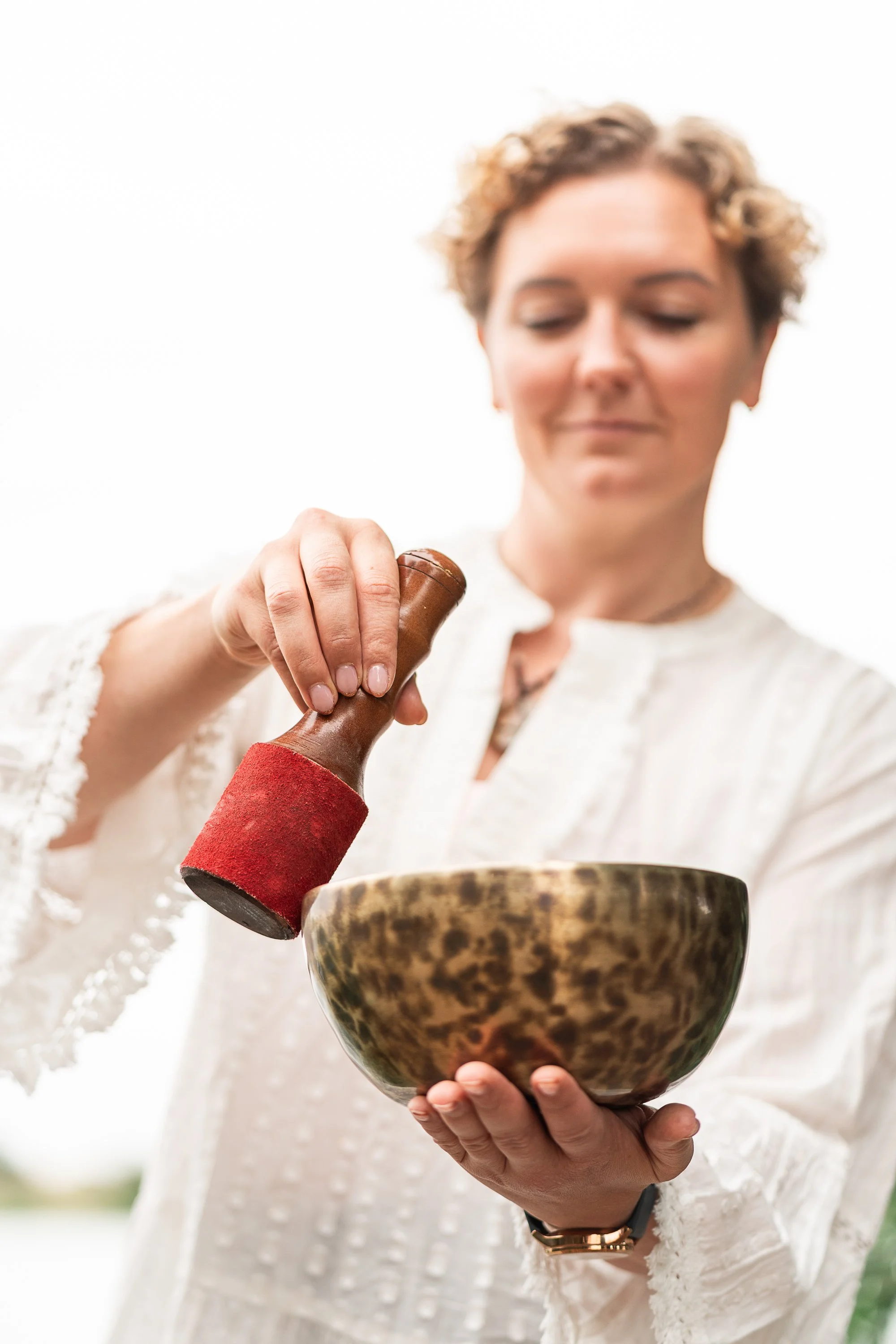 Close-up of Rowena Ramsell playing a Tibetan singing bowl during an outdoor sound healing session