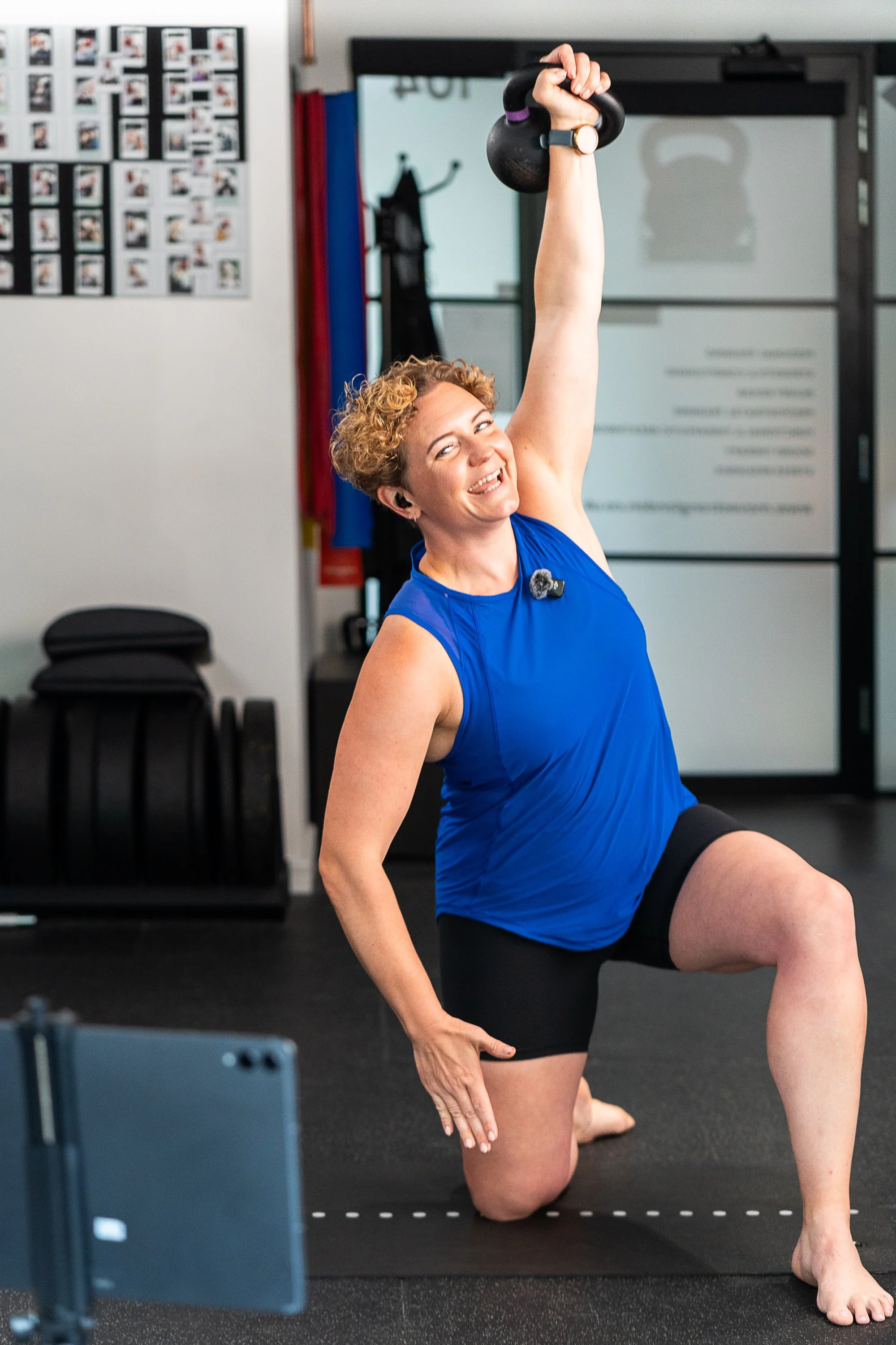 Personal trainer Rowena Ramsell performing an overhead kettlebell exercise in her London gym