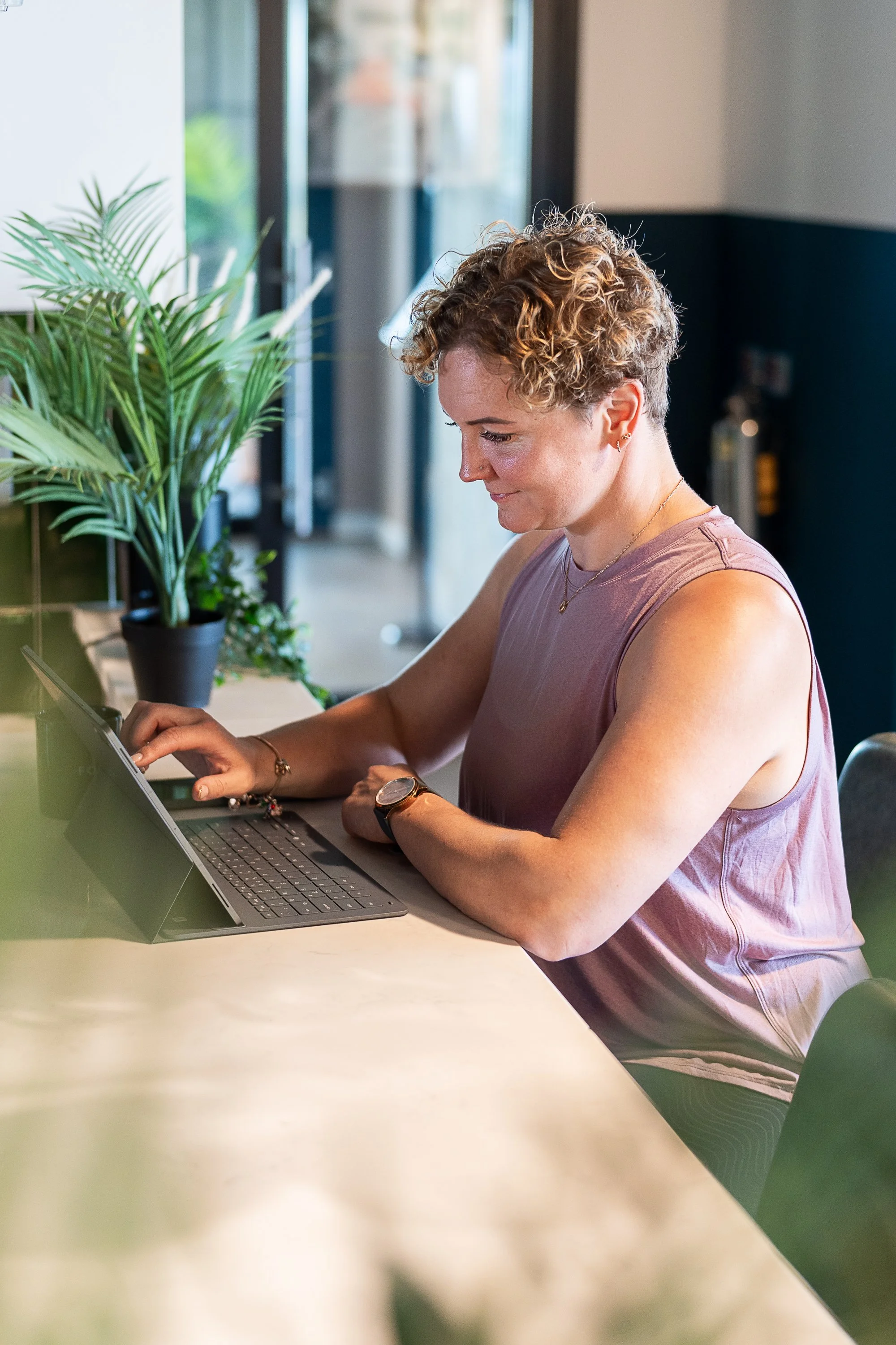 Wellness and fitness coach Rowena Ramsell working on her laptop at a gym counter