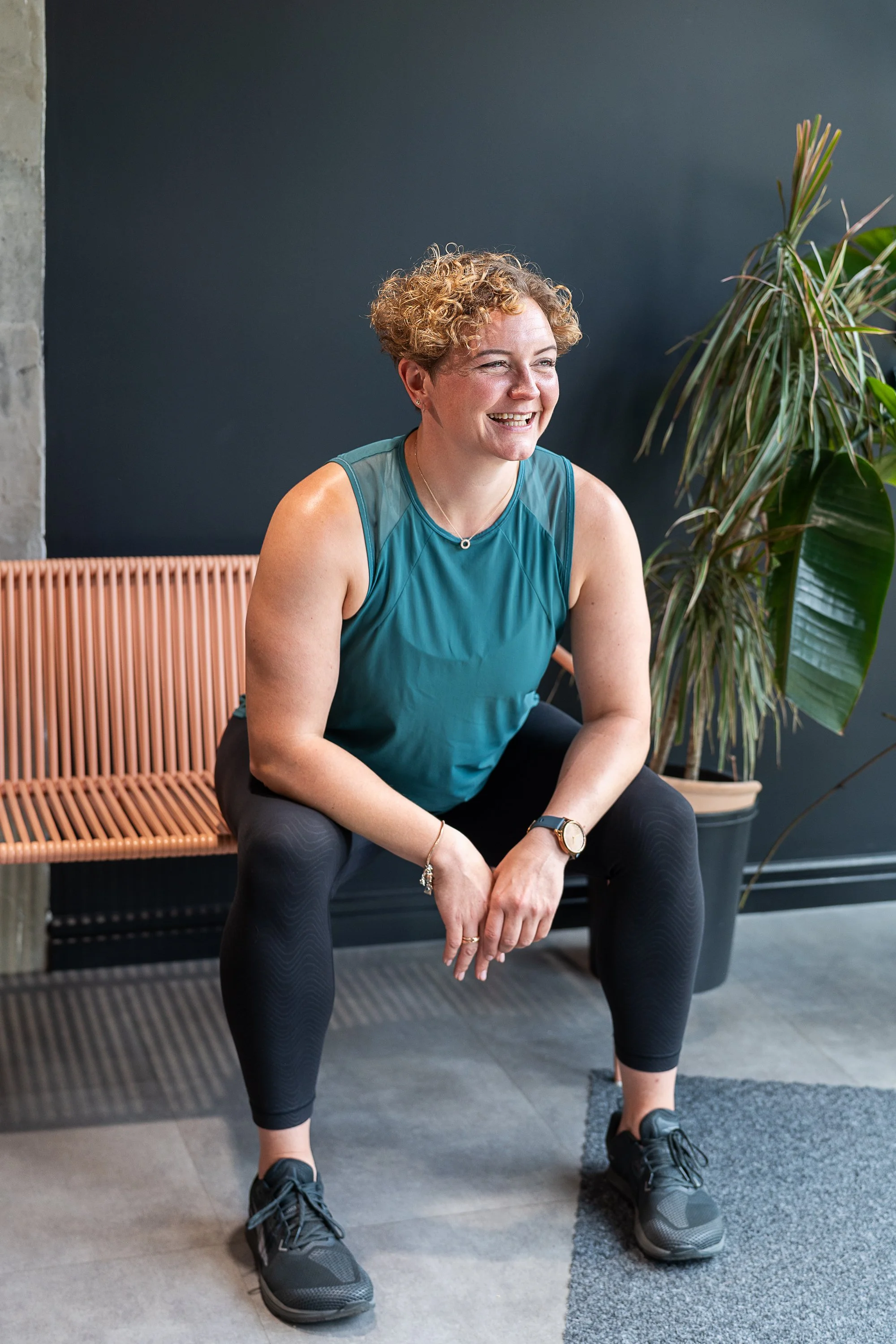 Relaxed lifestyle brand portrait of strength coach Rowena Ramsell sitting on a bench in the Foundry London