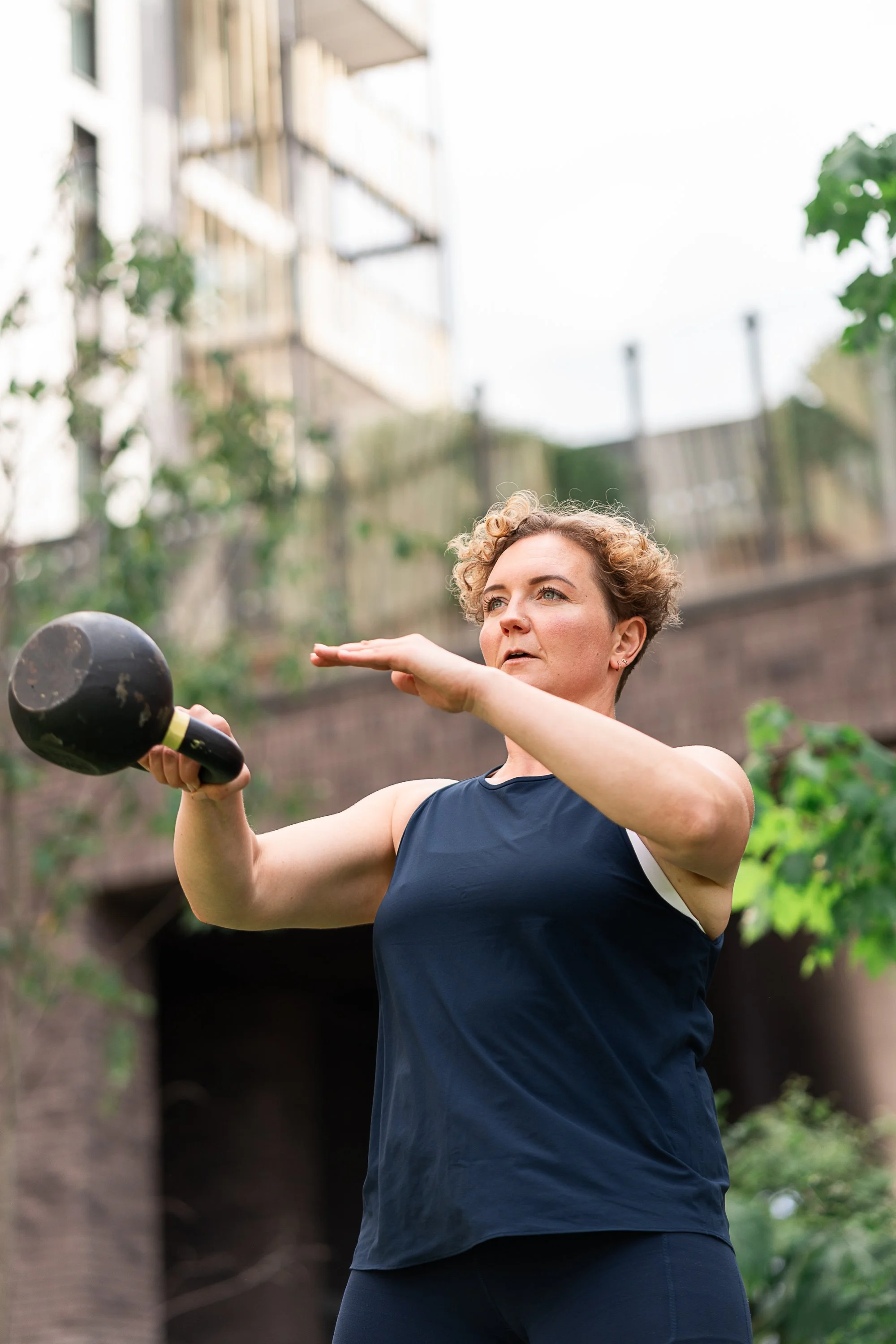 Rowena Ramsell demonstrating a kettlebell swing during an outdoor fitness photography shoot in London