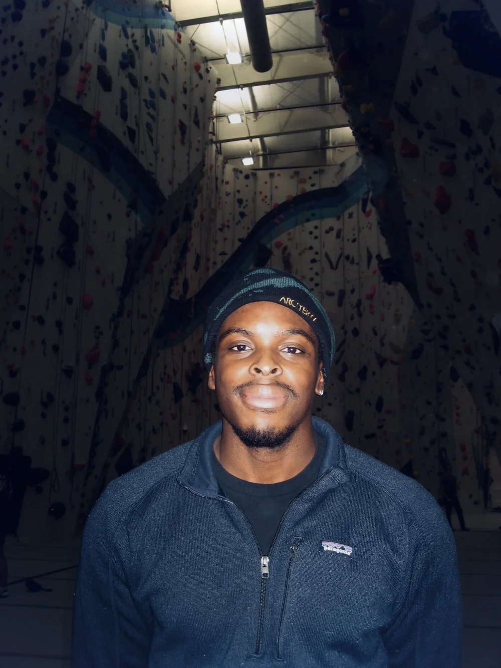Christopher Nwalupue in a black beanie at an indoor climbing gym