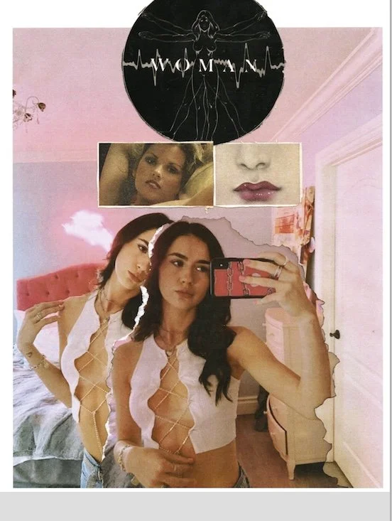 Two women taking a mirror selfie in a bedroom with pink walls and a black round wall art with the word "WOMAN" and an outline of a woman with outstretched arms. The woman in front has long black hair, is wearing a white top with a plunging neckline, 