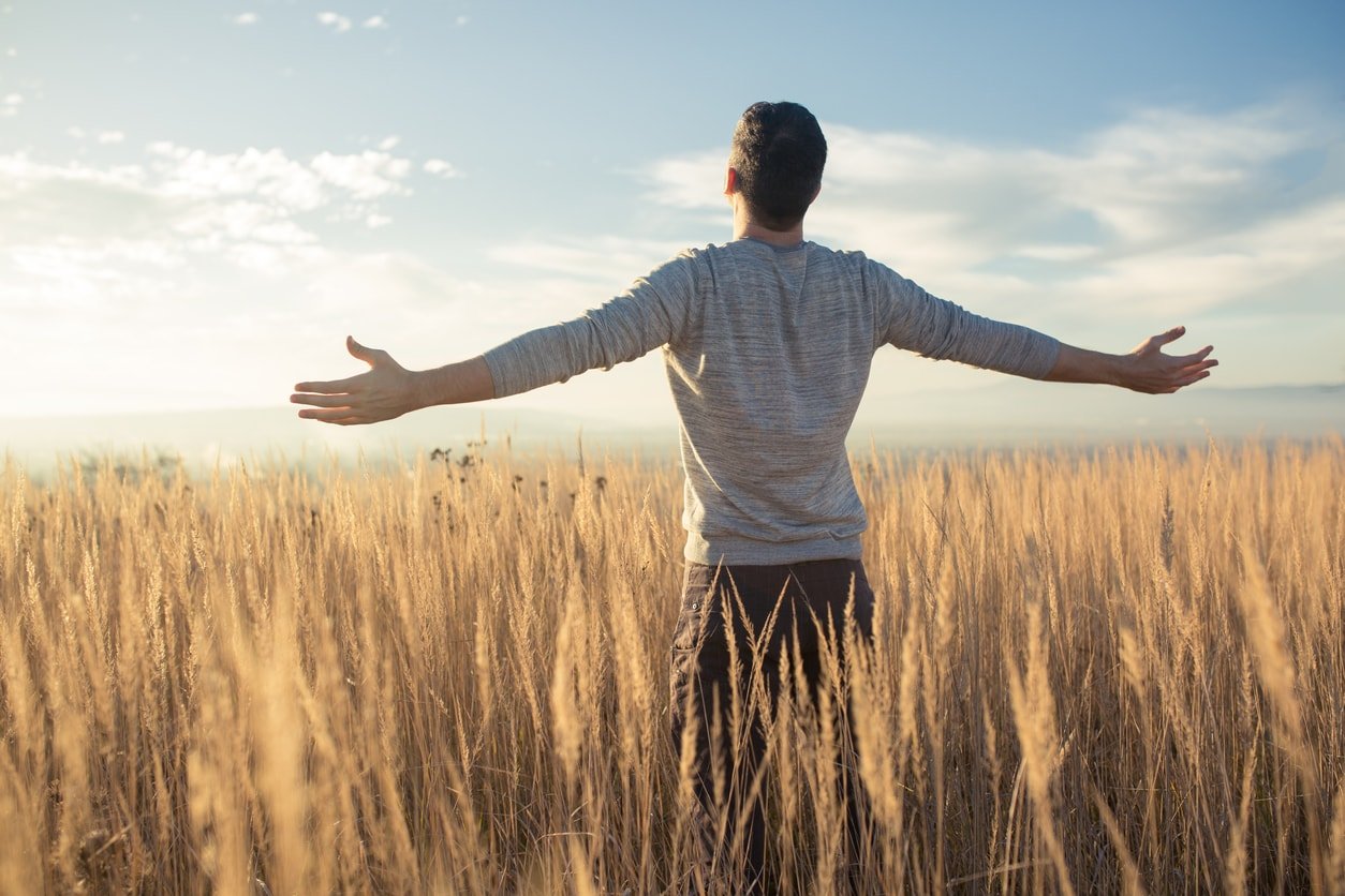 man-standing-in-wheat-field-with-arms-open-min.jpeg