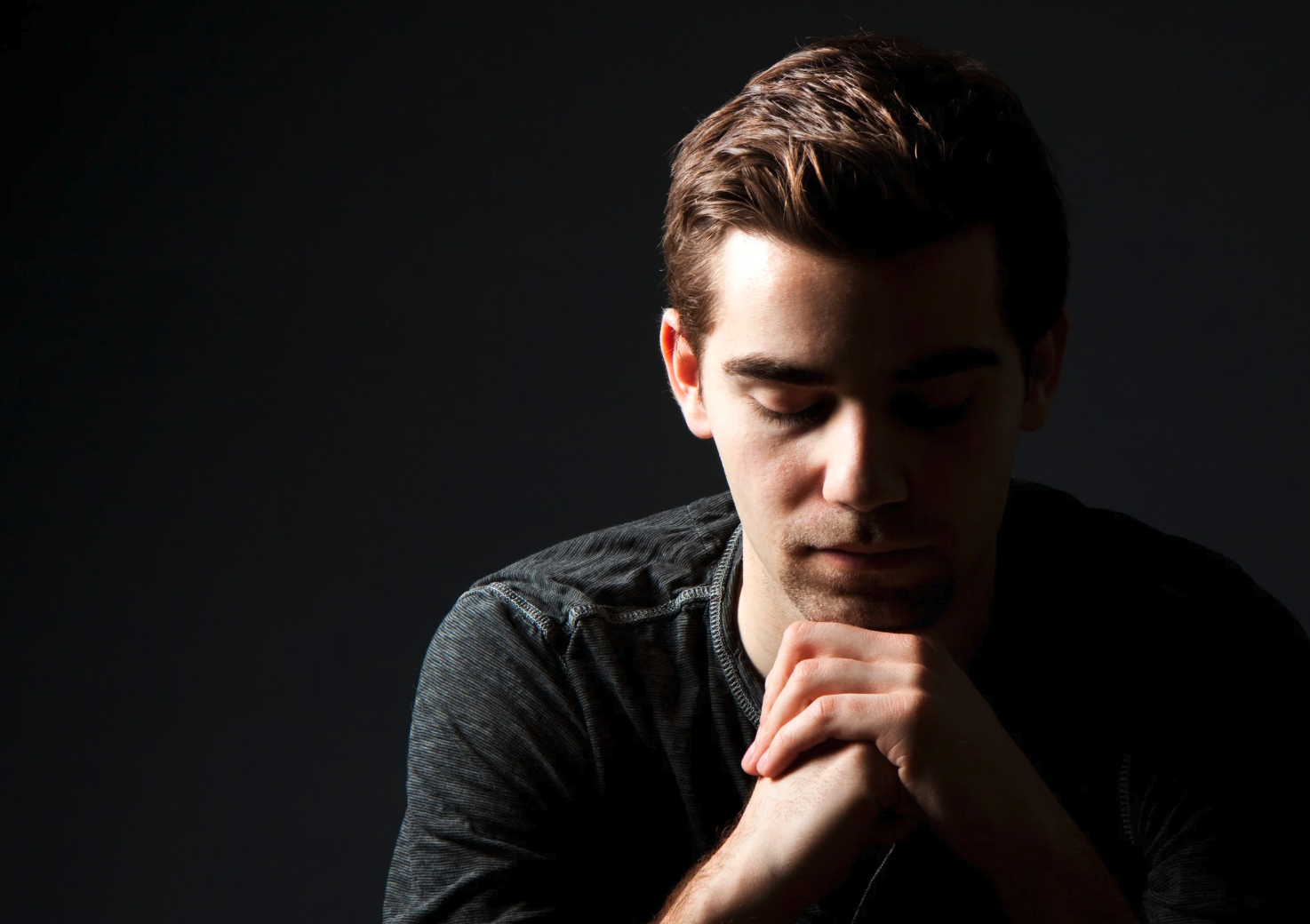 A man with his hands folded and sitting contemplatively