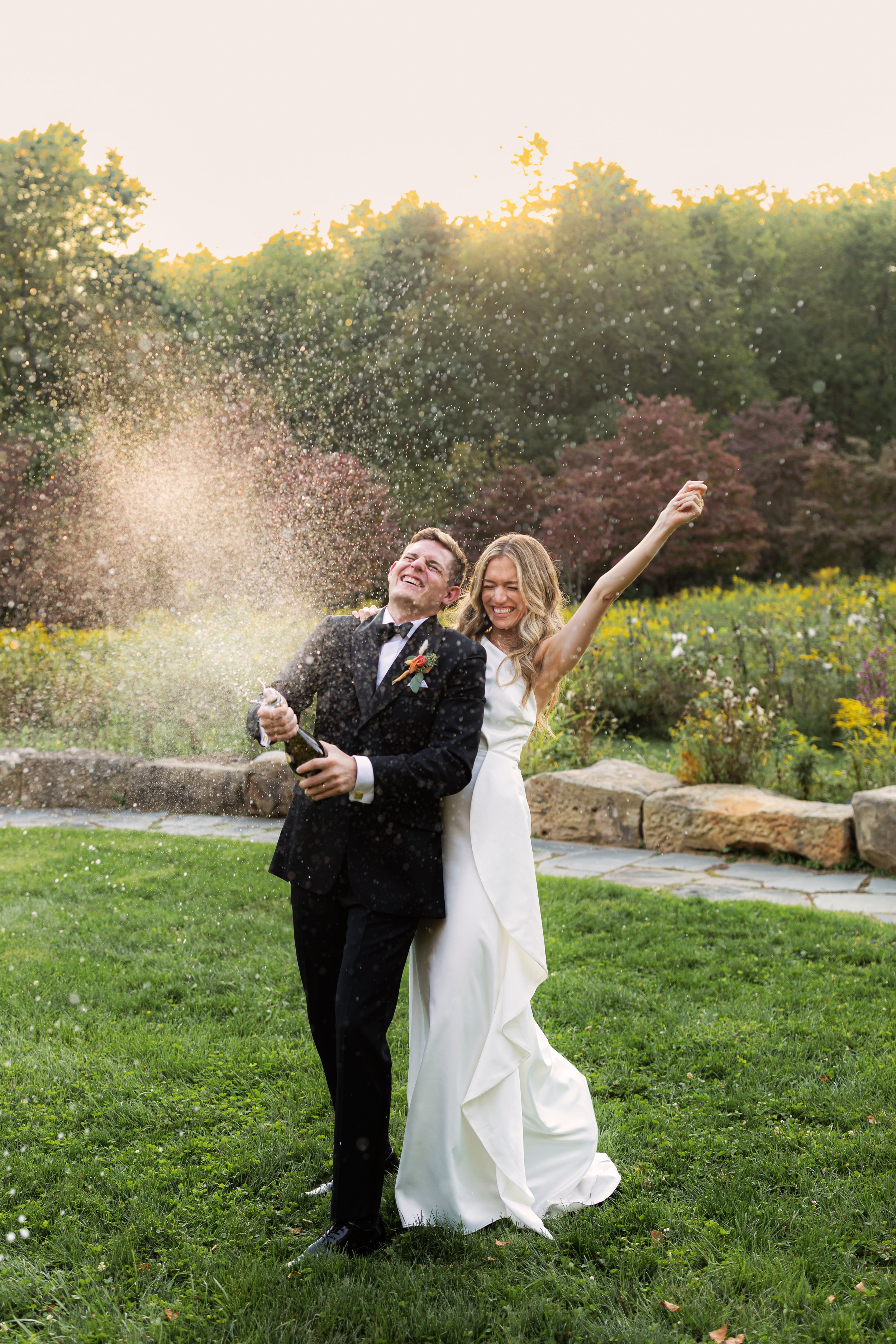  bride and groom pop a bottle of champagne during sunset at pittsburgh’s botanic gardens 