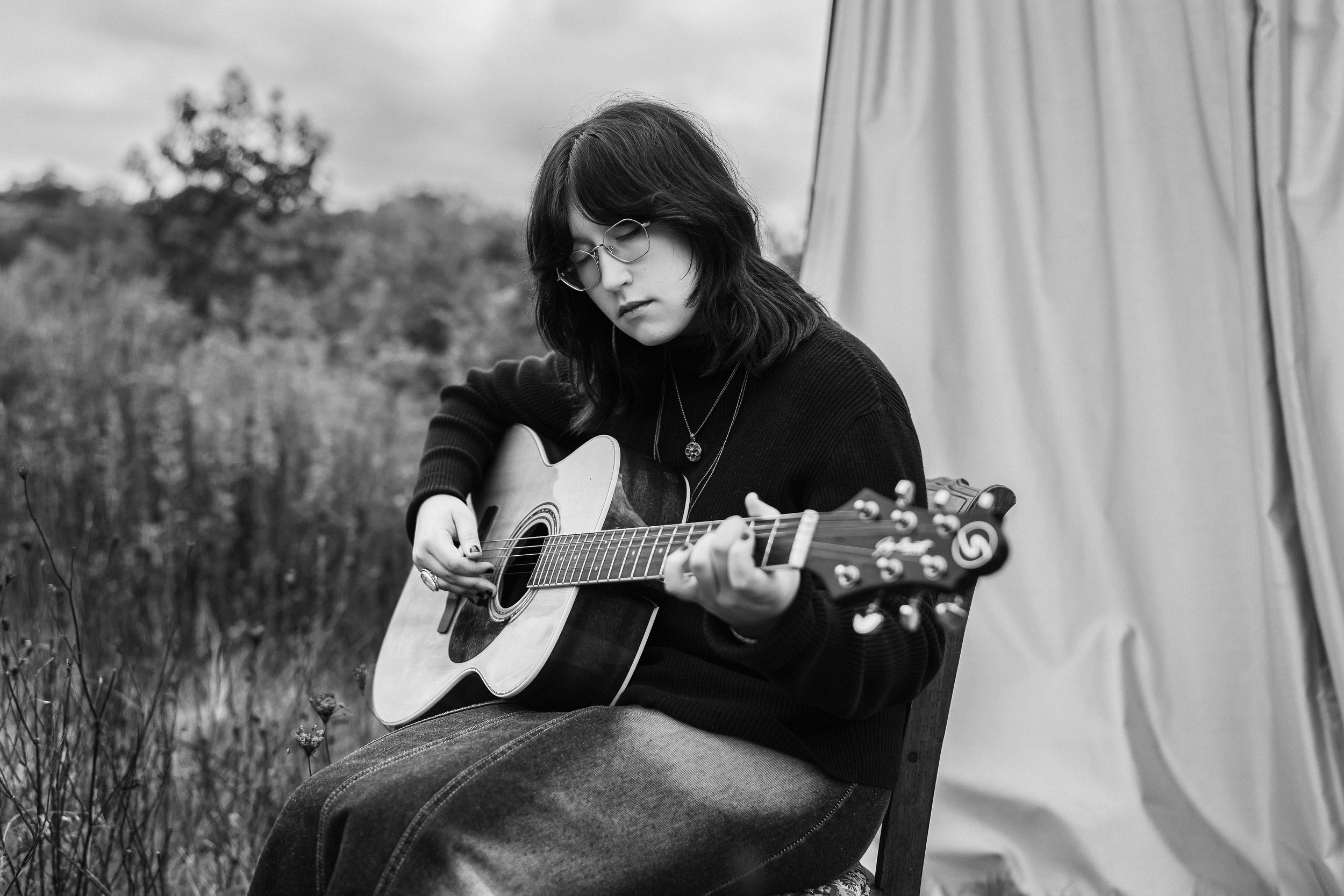 alternative high school senior plays an acoustic guitar in front of an outdoor studio at churchill valley greenway