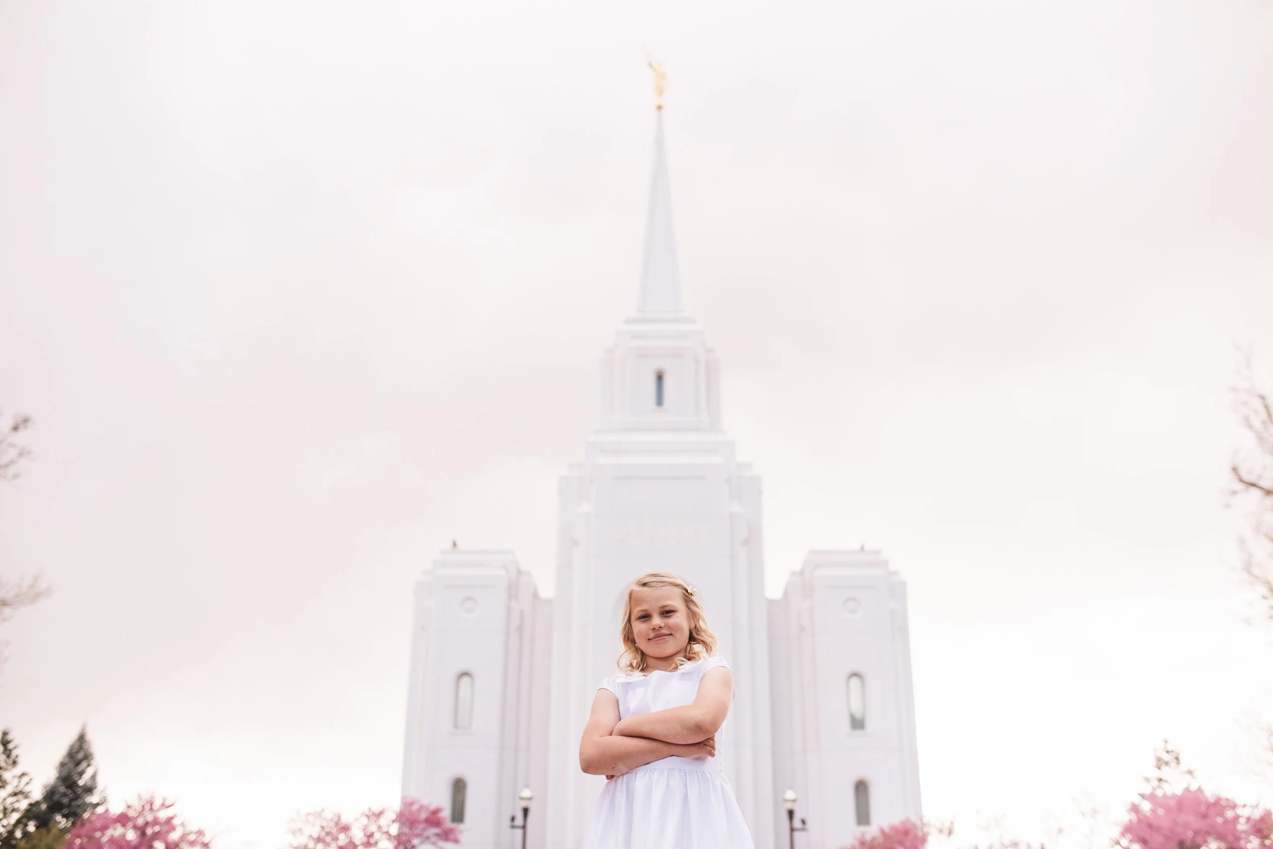 young girl posing in front of temple in white dress.