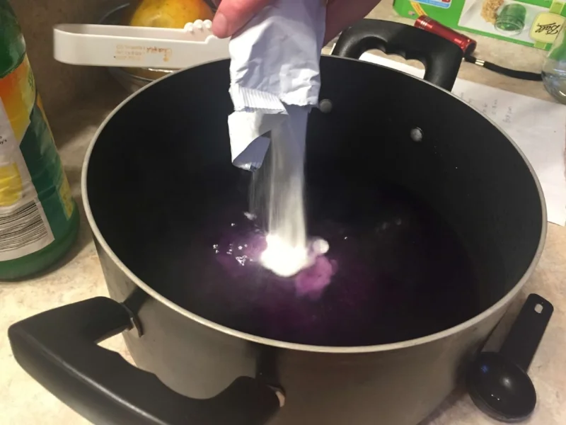 Adding powdered pectin to the violet and lemon juice.