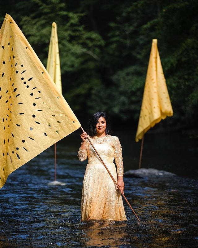 Artist Karina Puente @karinapuentearts made four large scale papel picado sunflower yellow flags, representing each year we&rsquo;ve gathered for our Full Circle Meal. They were installed in the water in pyramid bases up-creek at the head of the tabl