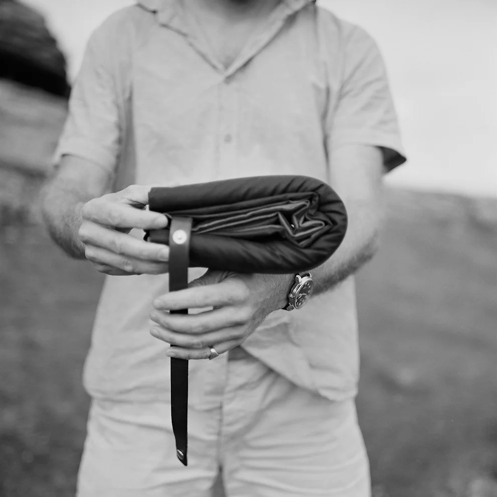 With the two rolled ends brought together, take the strap from the center and wrap around the outside of the whole roll.