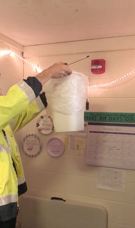 A Facilities worker holds a bucket up to a leaking roof in the Dana Residence Hall. 