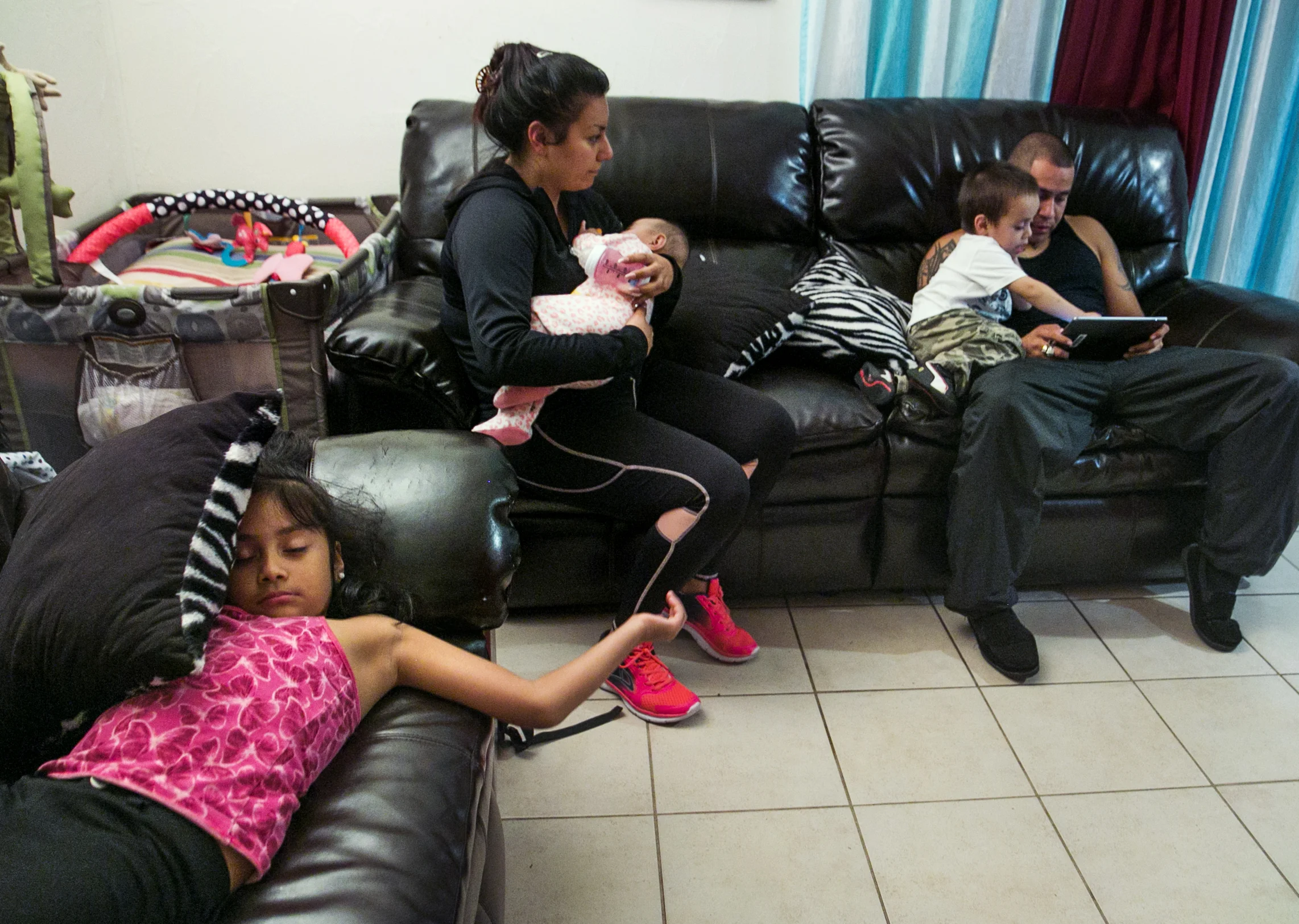  On Monday Feb. 29, 2016, Abel Lopez read to two-year-old Angel Jaimes while spending time with the toddler's family in their home in Rundberg. Seven-year-old Lunna Gomez flipped onto the couch after playing with their dog, Bella, and Katie Ugarte ro