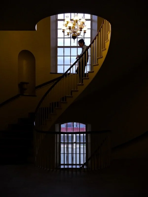Person descending a dark, spiraling staircase.