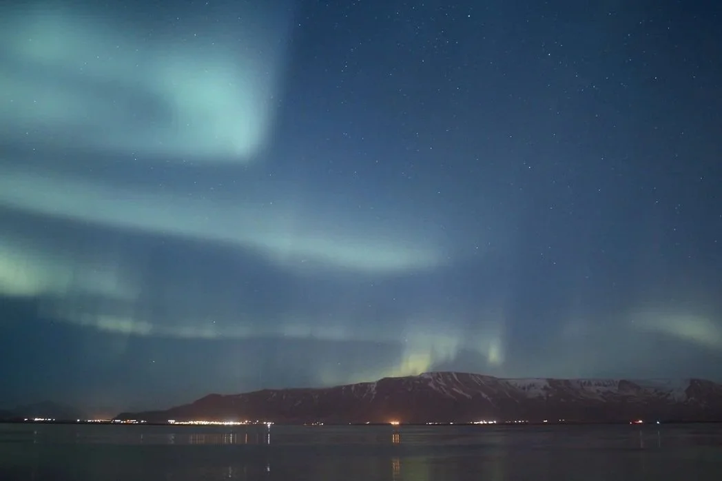 Image of the aurora borealis over a mountain in Reykjavik, Iceland.