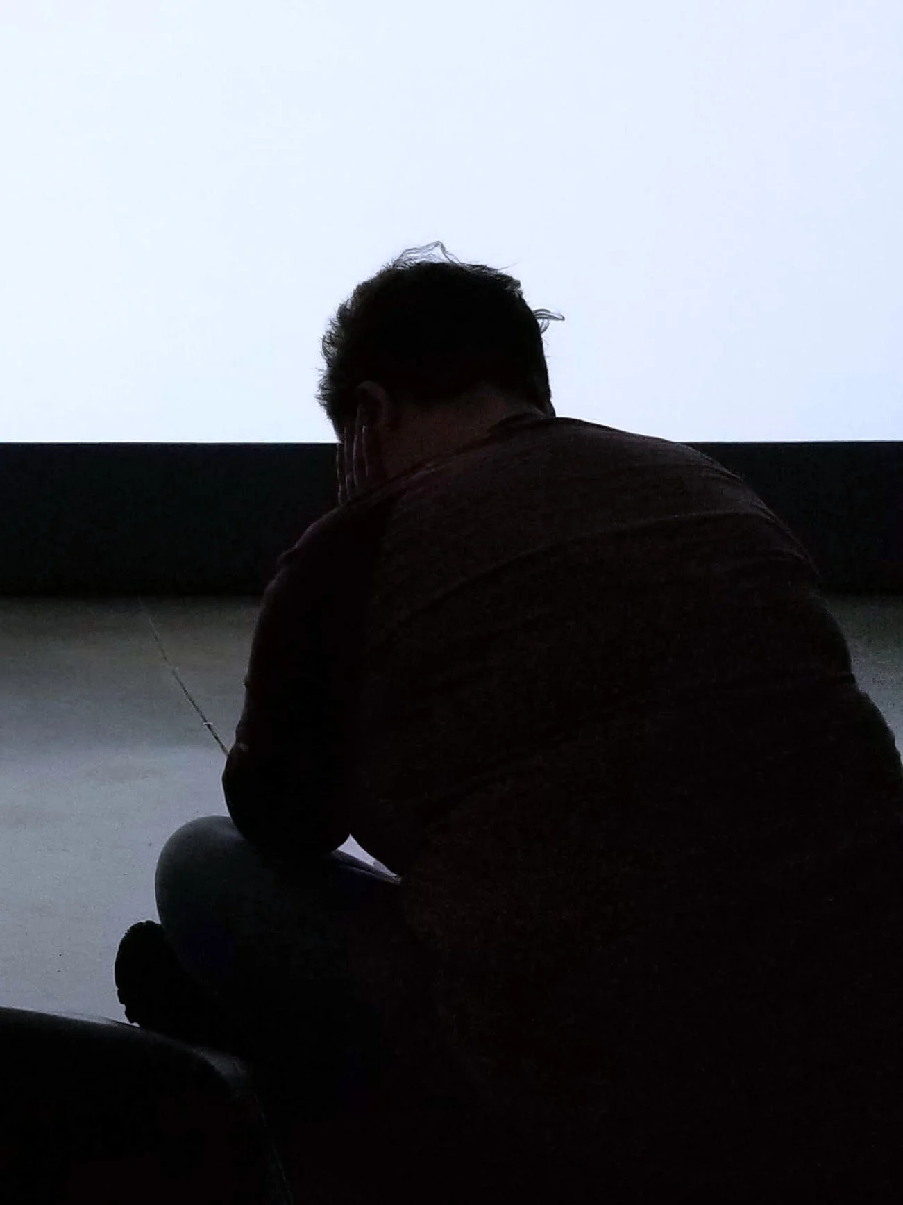 Image of a person silhouetted, sitting alone.