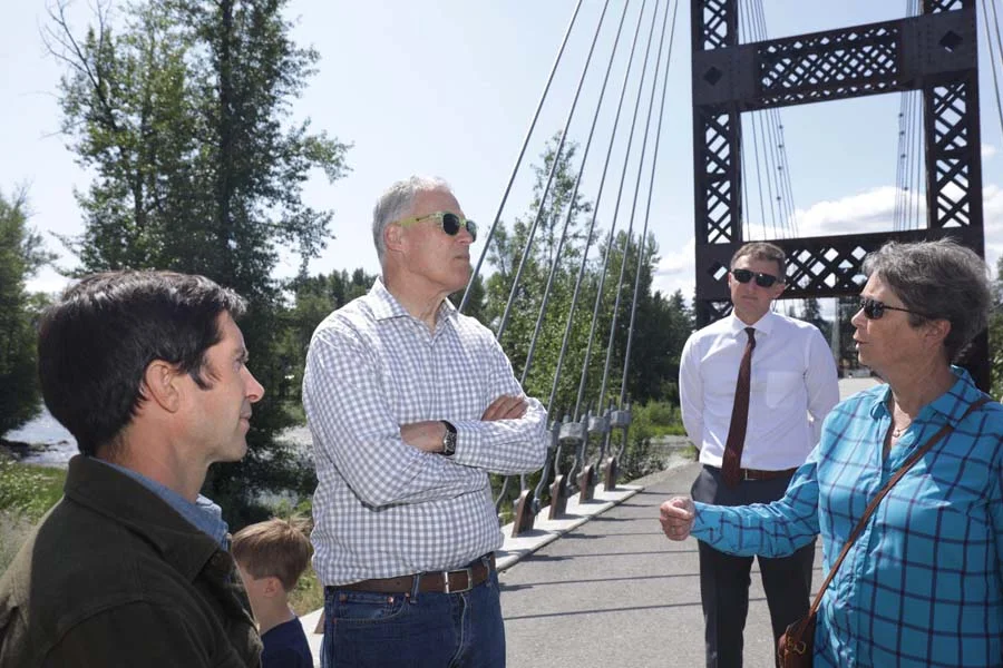 Photo by Ryan Bell Washington Gov. Jay Inslee chatted with Winthrop Mayor Sally Ranzau at the Spring Creek Bridge, as Twisp Town Council member Hans Smith looked on. Inslee also visited Twisp and Pateros on Friday (July 19).