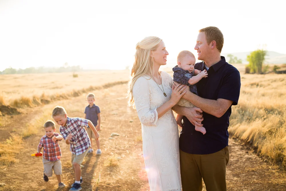 Tonya Edwards | Oroville Family Photographer | parents holding baby while older sons are playing