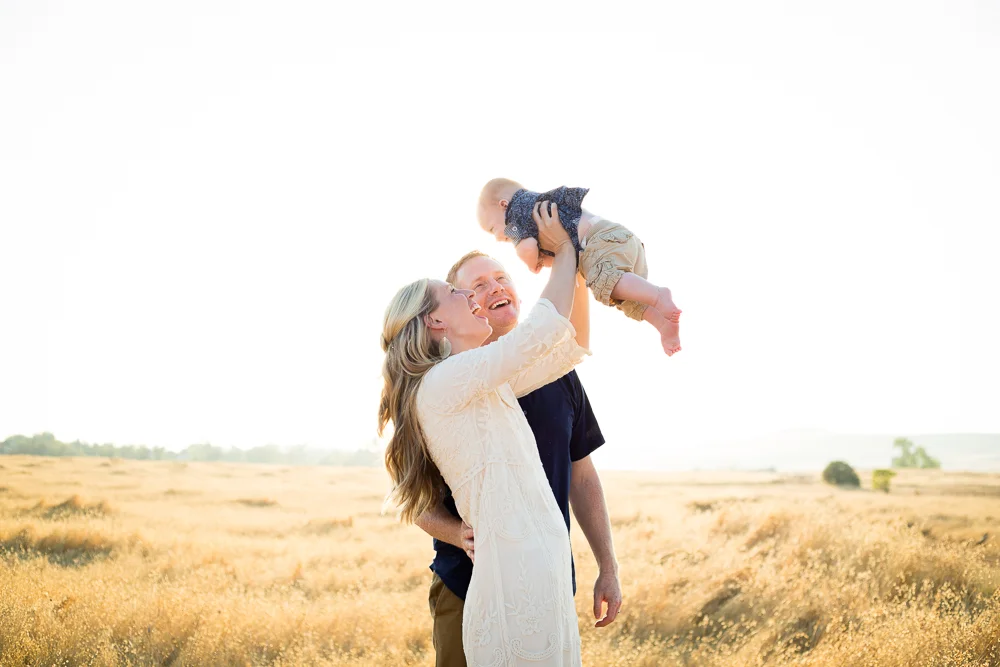 Tonya Edwards | Oroville Family Photographer | mother holding baby in the air with father watching