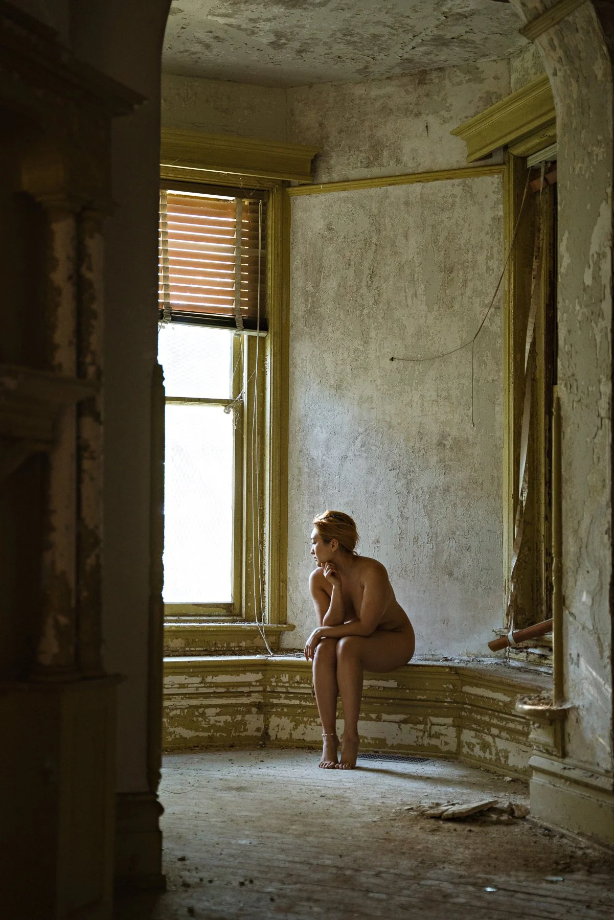 nude model sitting in an abandoned mansion