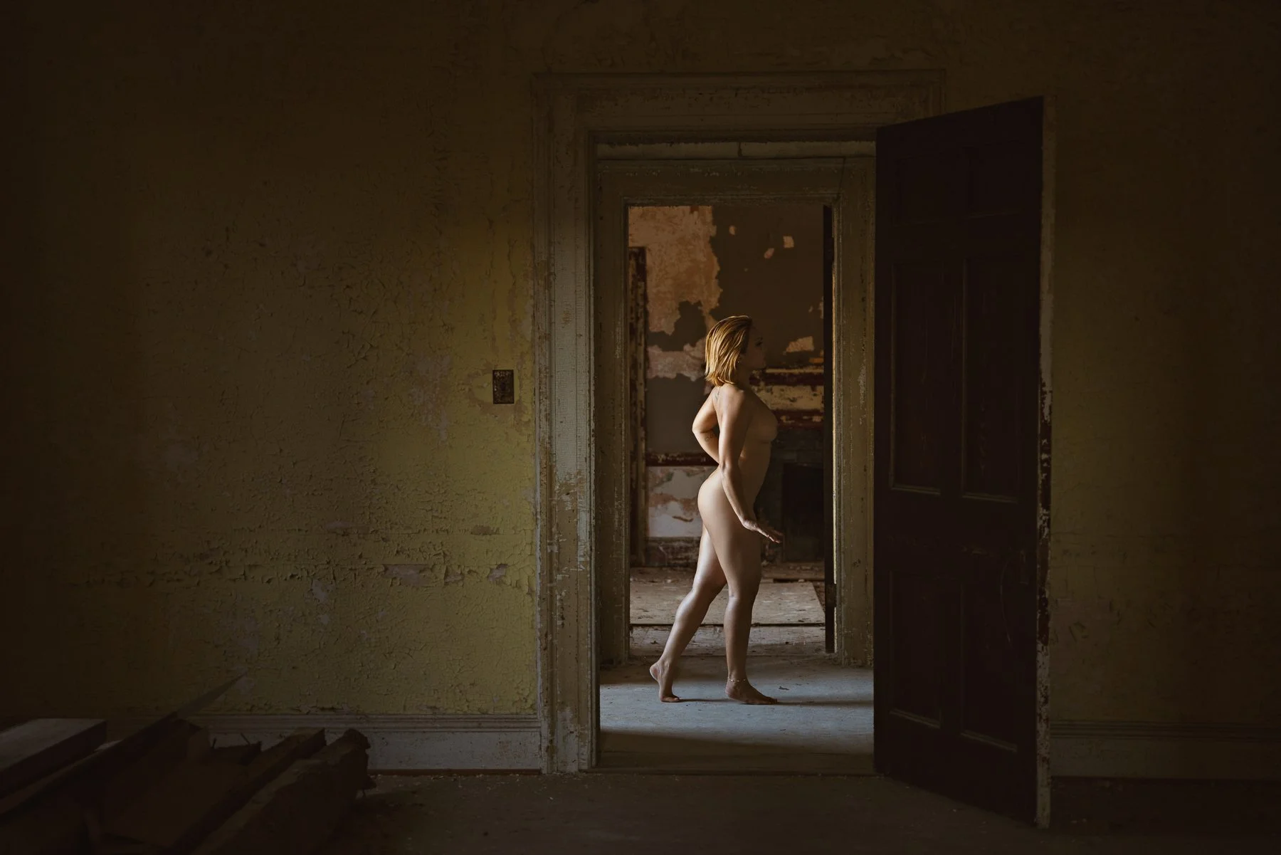 nude model walking thru doorway in an abandoned mansion