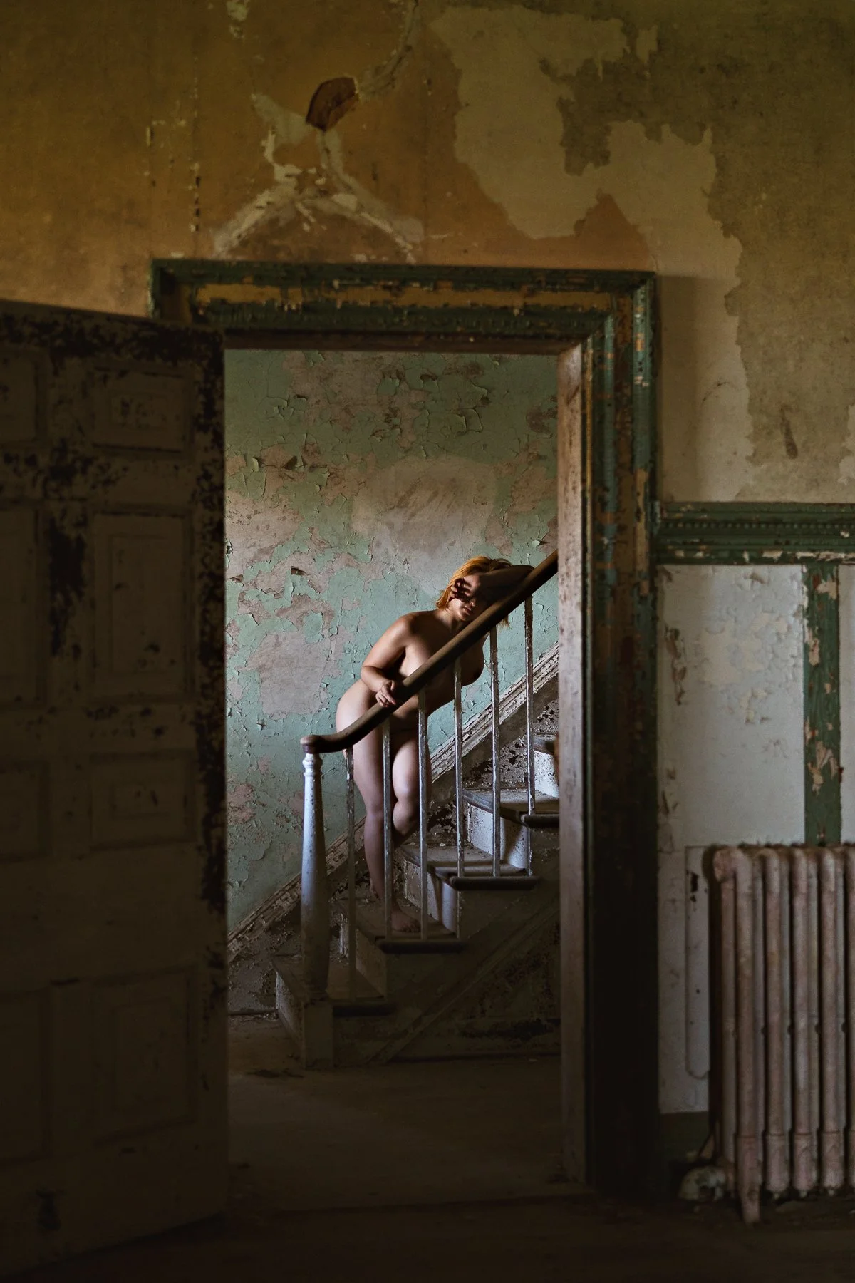nude model posing on stairway in an abandoned mansion